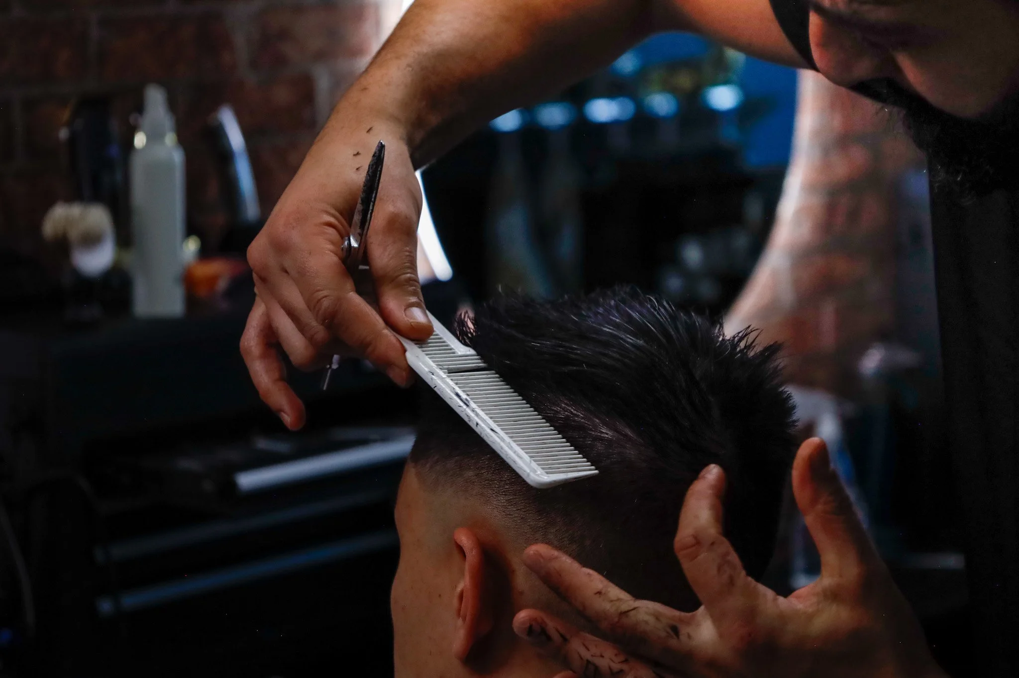 Barber giving a haircut with a comb and scissors in a barbershop.