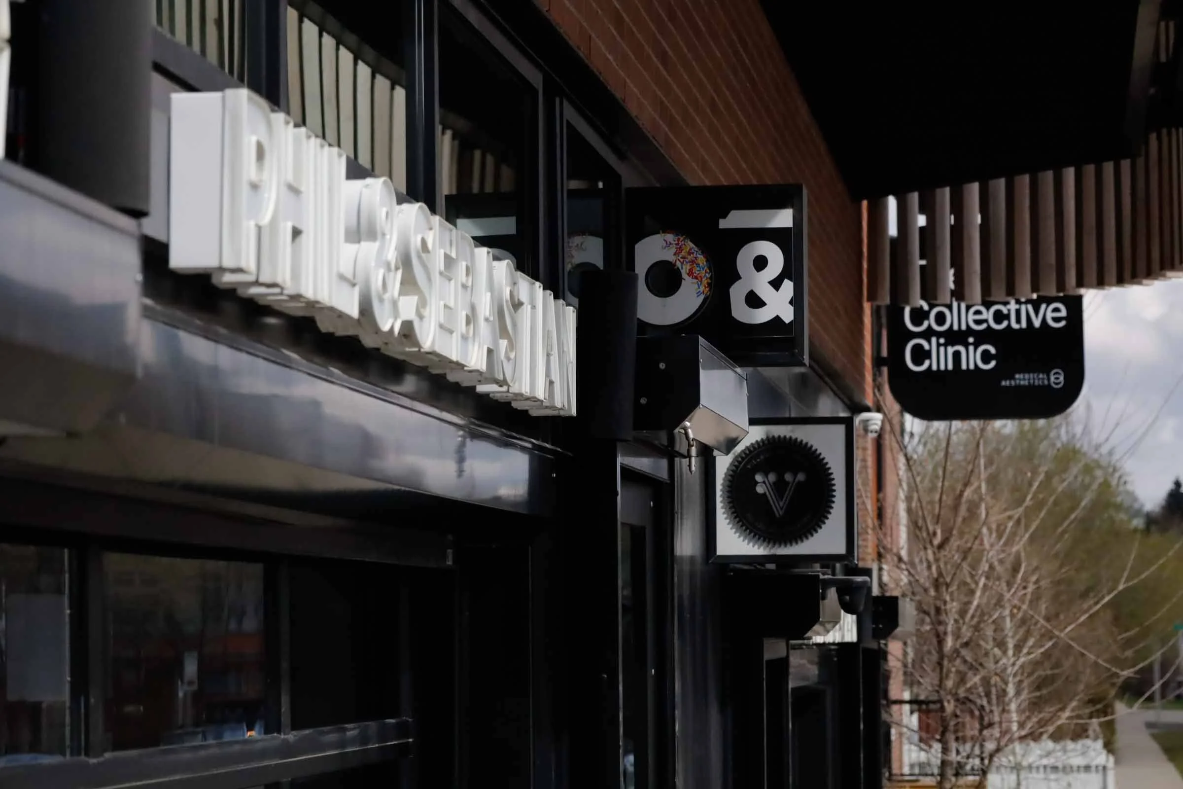 Signage for a business called 'E & 9' and 'Collective Clinic' outside a building with brick exterior and wooden accents.