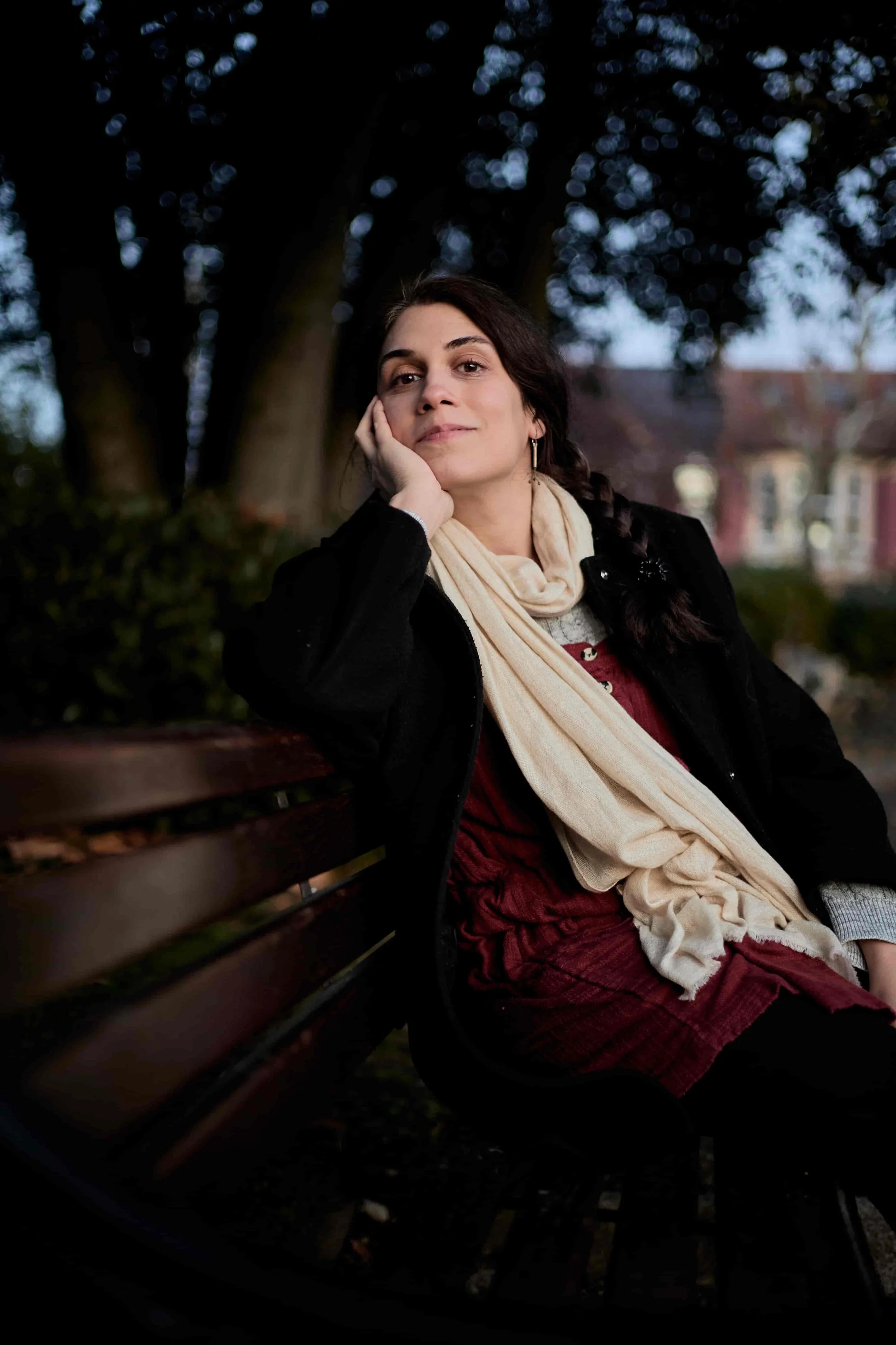 Carina resting her head on her hand on a park bench, smiling at the camera