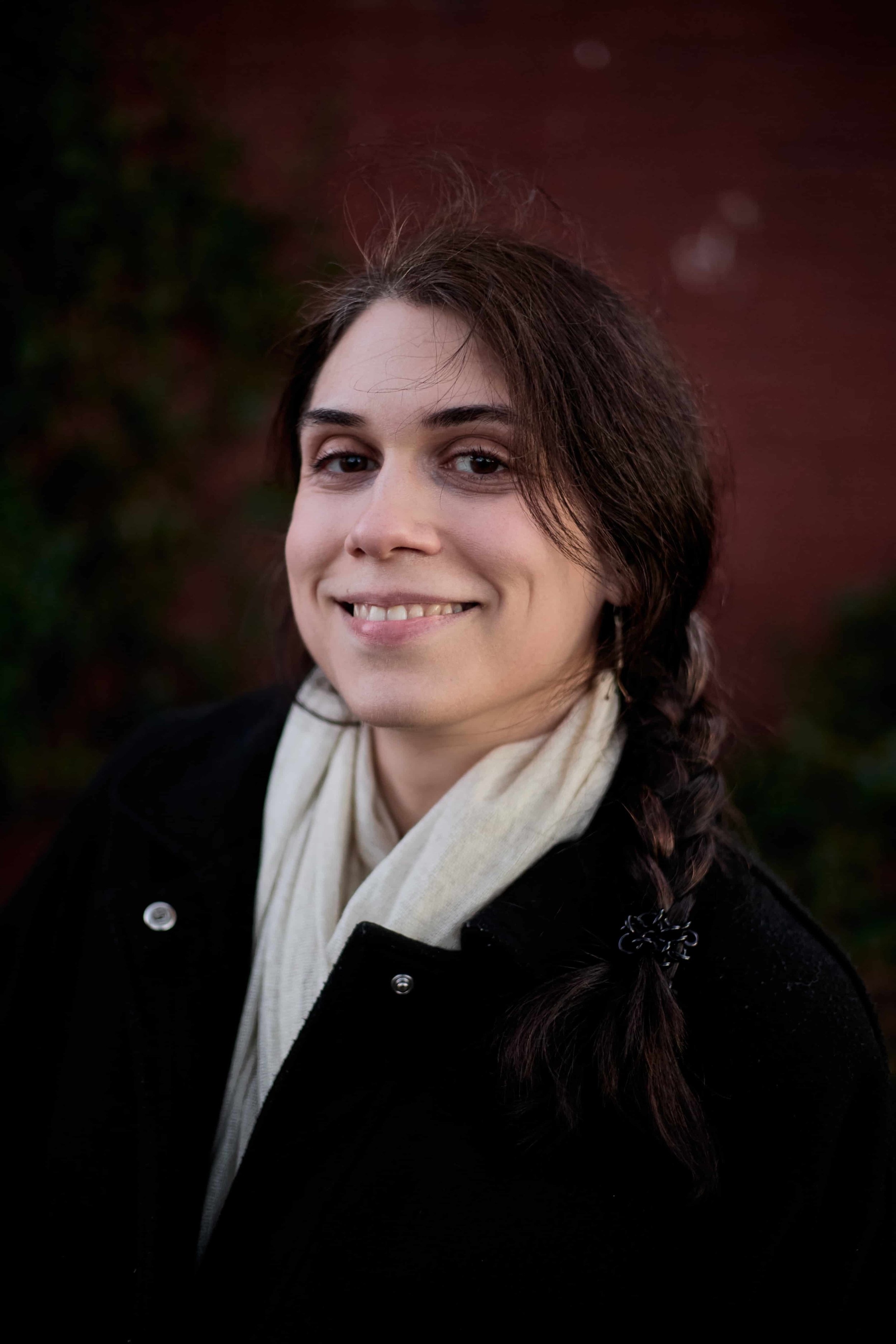 Carina, a CBT therapist offering intensive therapy, smiling outside wearing a beige scarf and black coat