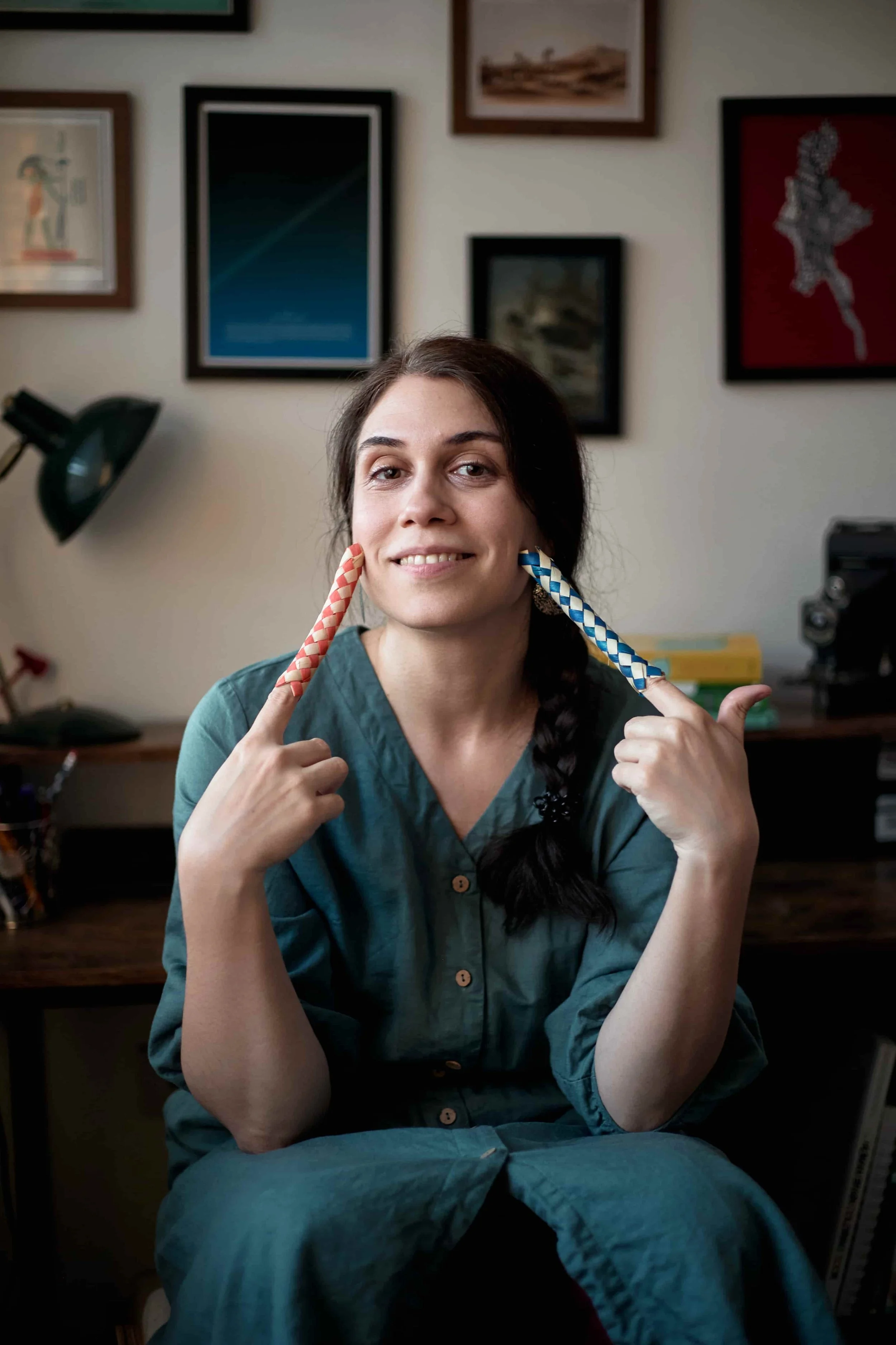 Carina, an online BABCP-Accredited CBT Therapist, in a teal dress, with Chinese fingertraps on each index finger