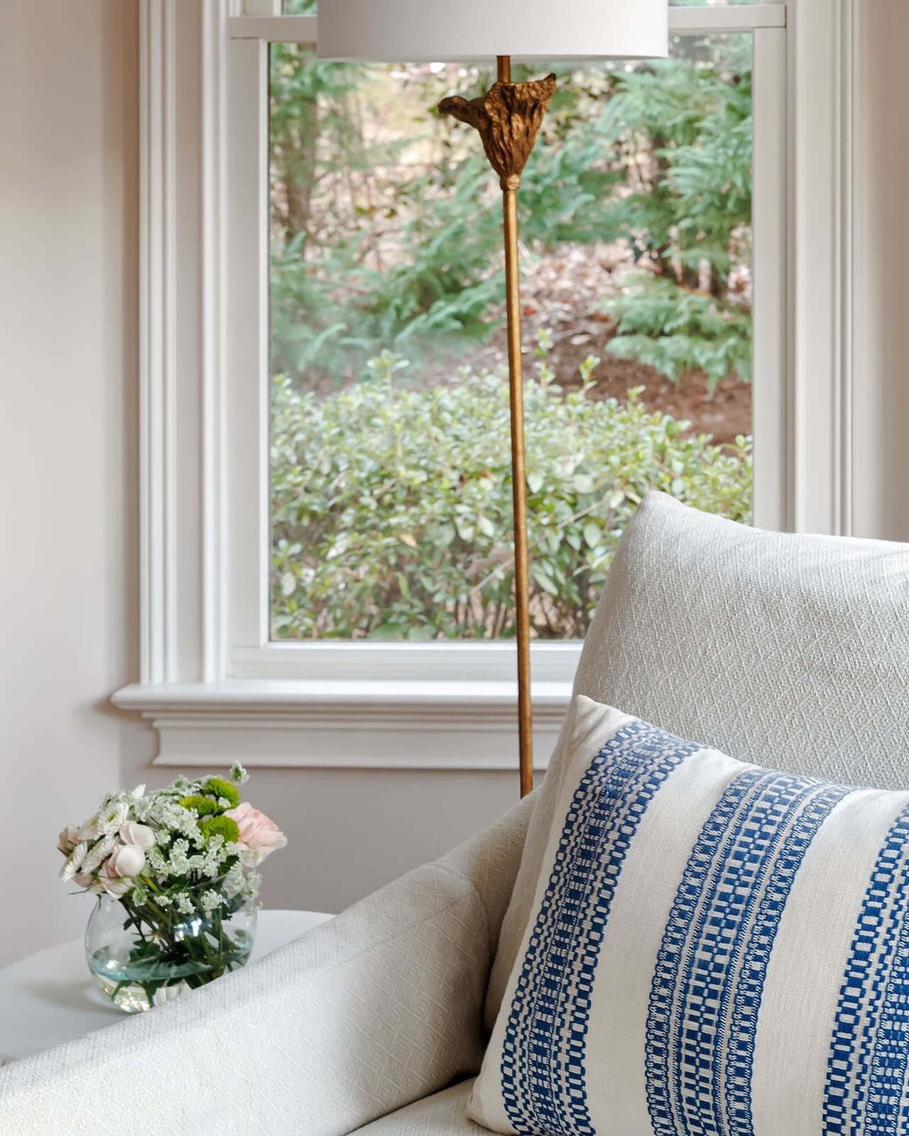This close up in the primary bedroom at our #CDWestburyProject has one of our favorite lighting moments. The lovely brass floor lamp nestled in the bay window creates the perfect reading nook. Paired with a cute lumbar pillow on the big, comfy lounge