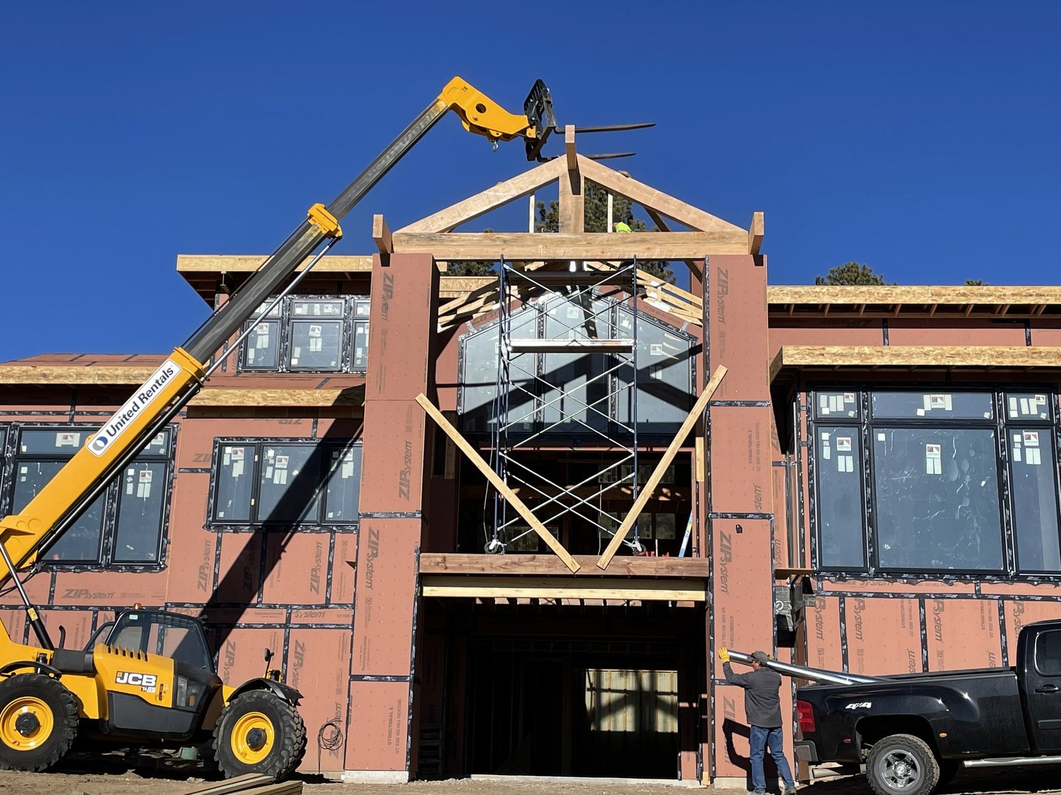 Telehandler setting a timber truss on a brick building