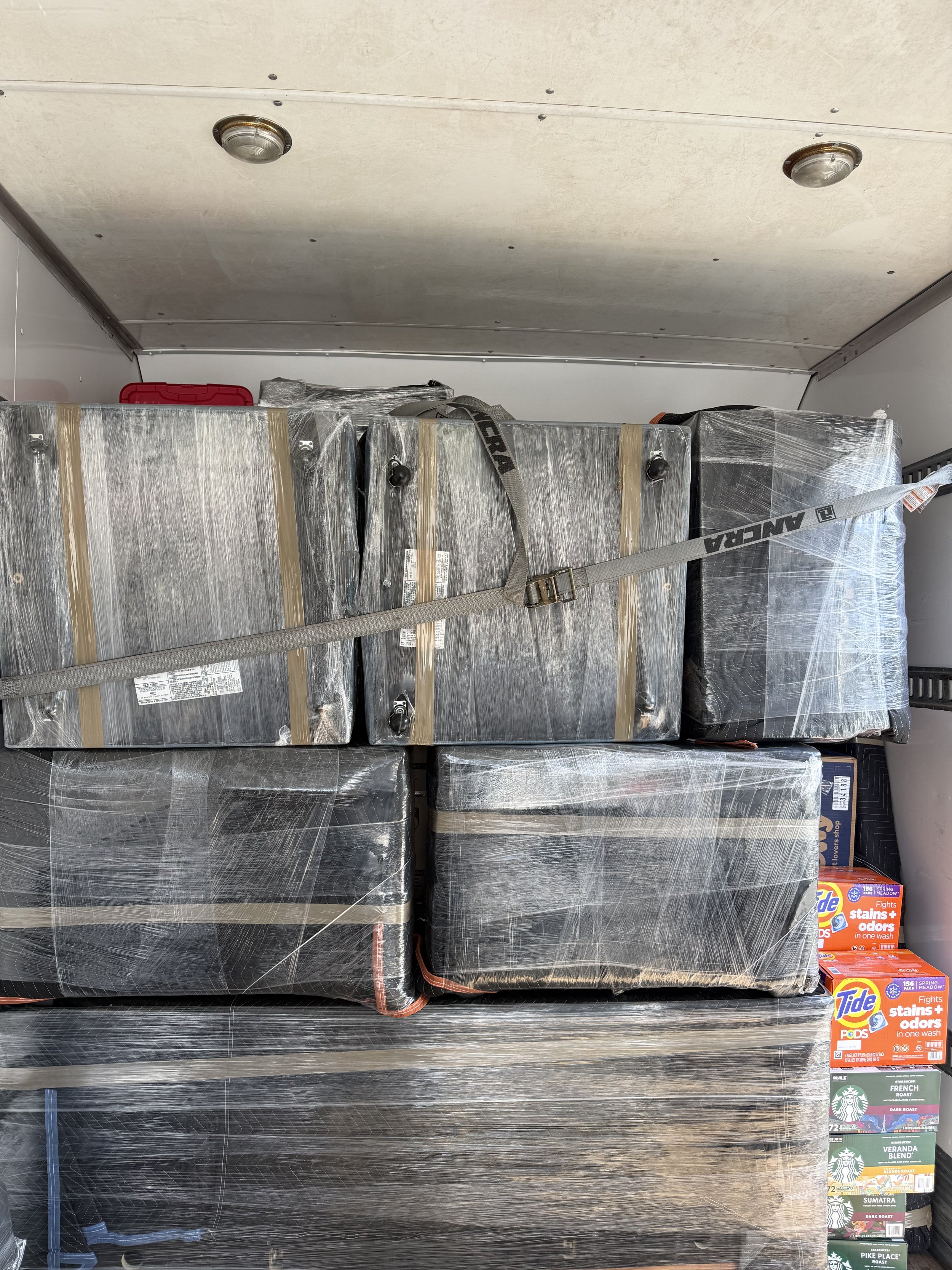Stacks of wrapped appliances or boxes secured with straps inside a vehicle or storage area.