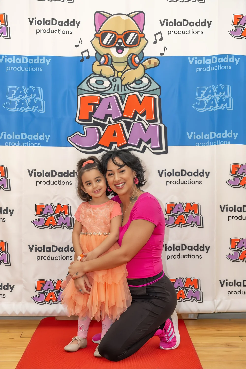 A mom and daughter hugging at the Fam Jam step and repeat