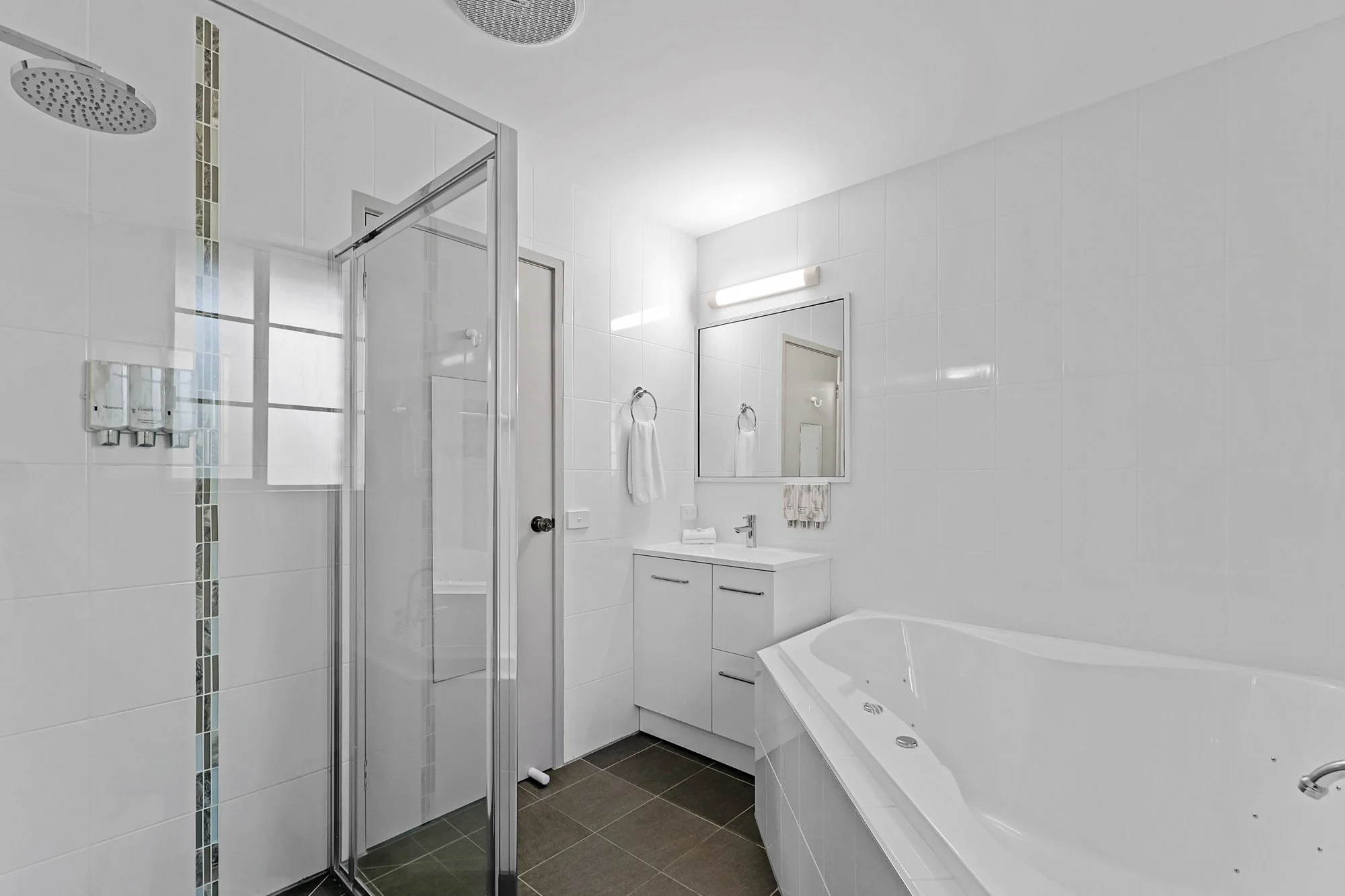 Luxury hotel bathroom featuring spa bath, walk-in shower and marble countertop.