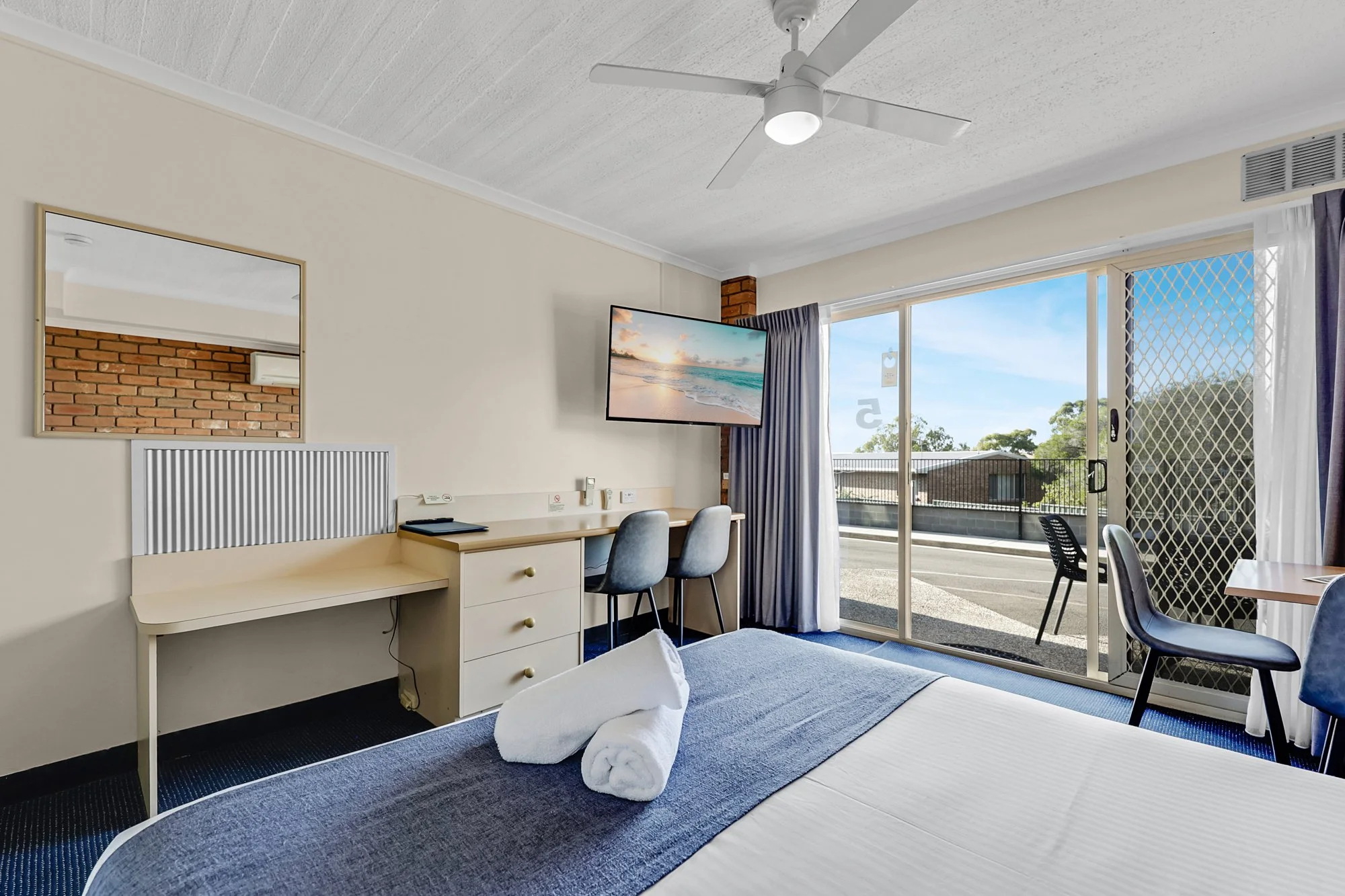 Spacious hotel suite bedroom with king bed, modern finishes, and balcony view. Hotel Photography.