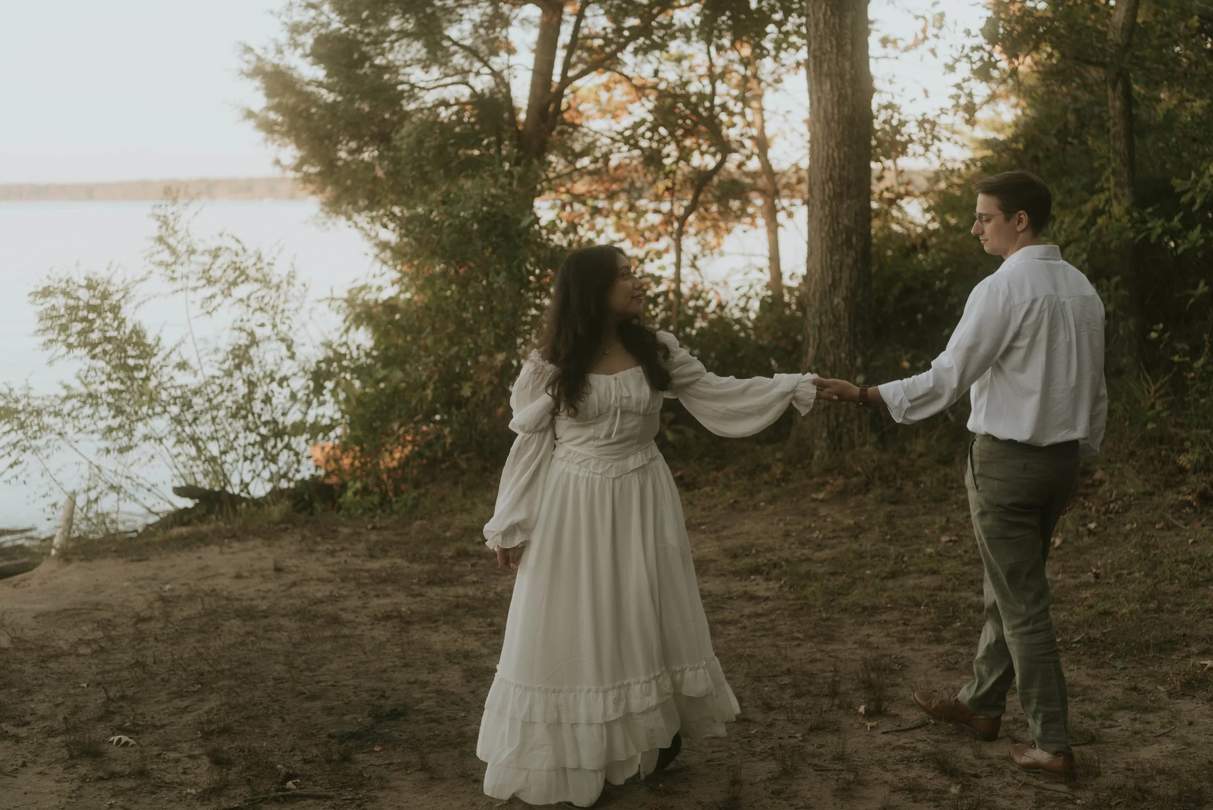Engaged couple holding hands along the waterfront during a film-inspired engagement session at Chapman State Park in Indian Head, Maryland, photographed in the DC, Maryland, and Virginia (DMV) area.