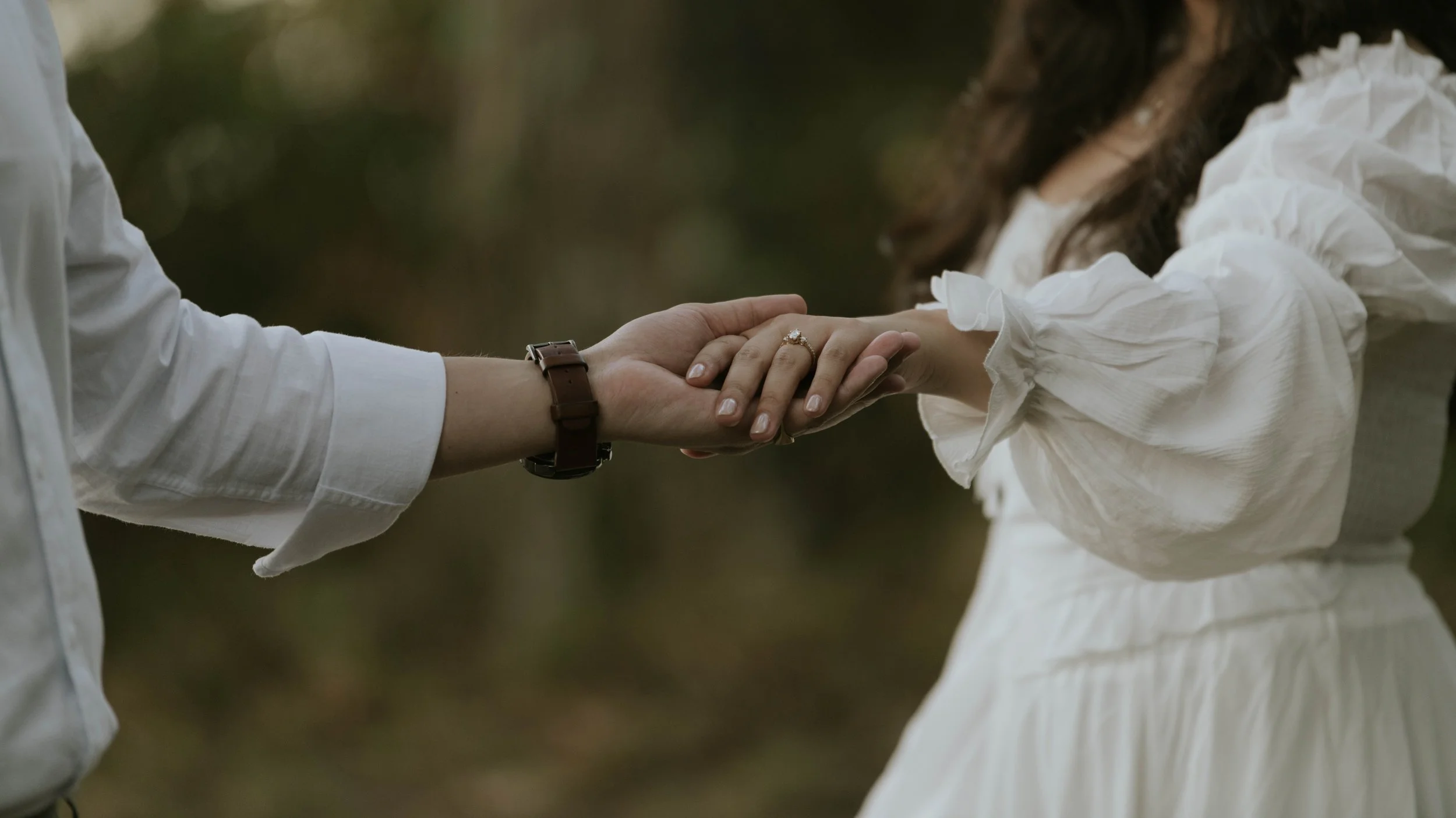 Close-up of hands during a green, film-inspired engagement session at Chapman State Park in Southern Maryland, showing the engagement ring.