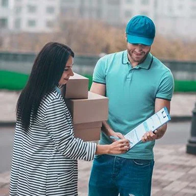 A man and woman outside with packages and a tablet, looking at the tablet together.