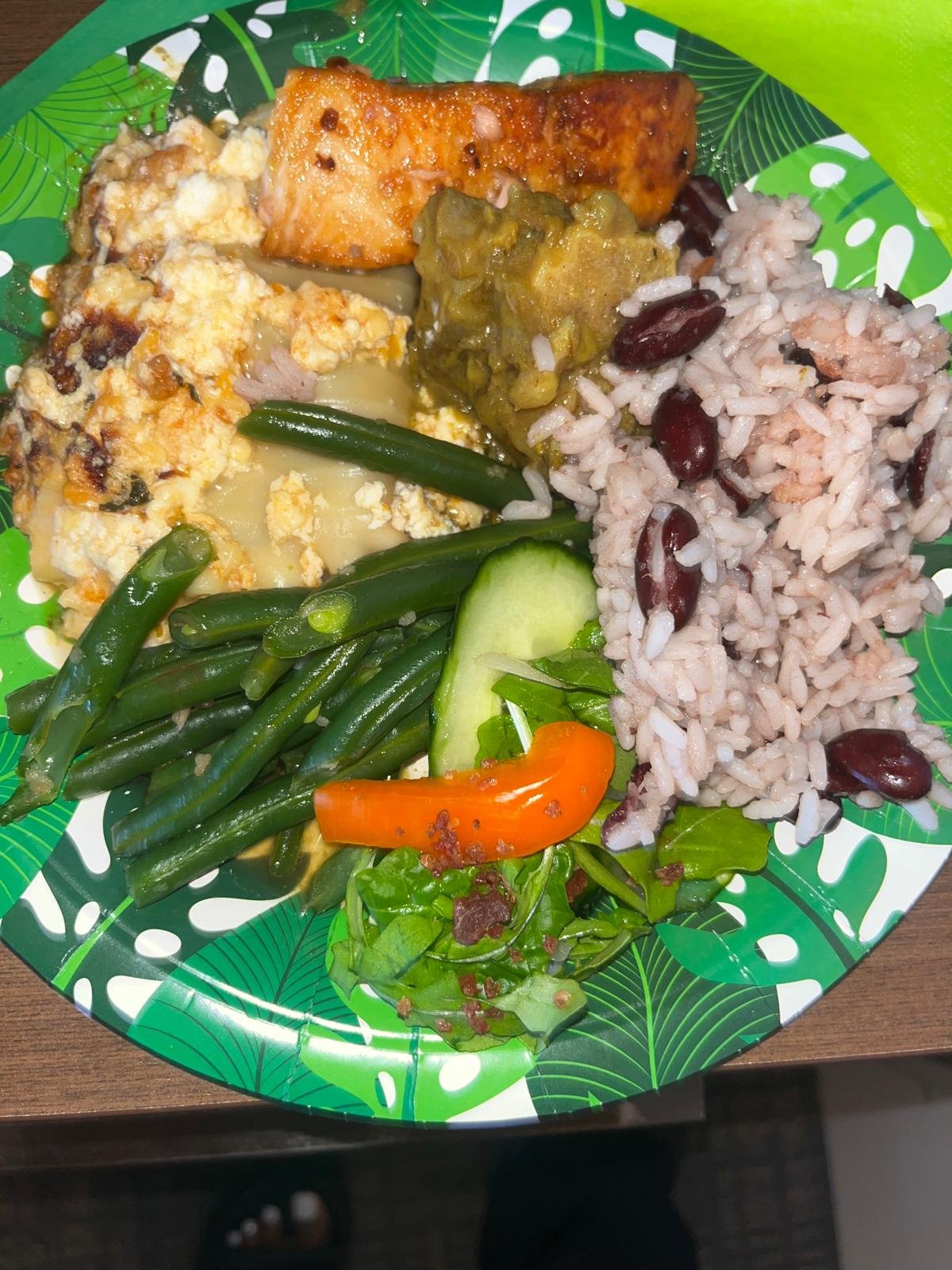 The menu includes curry goat, honey-baked salmon, peas & rice, lasagna, green bean casserole, and salad—a well-rounded lunch!