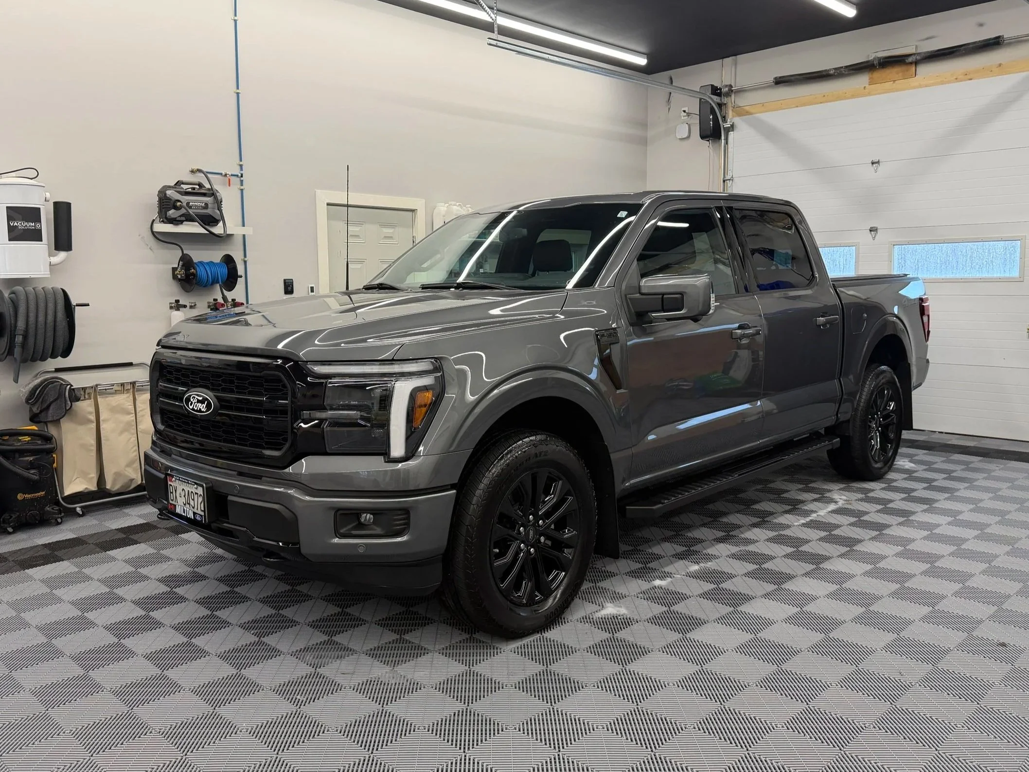 Gray Ford pickup truck parked inside a garage with a checkered black-and-gray floor.