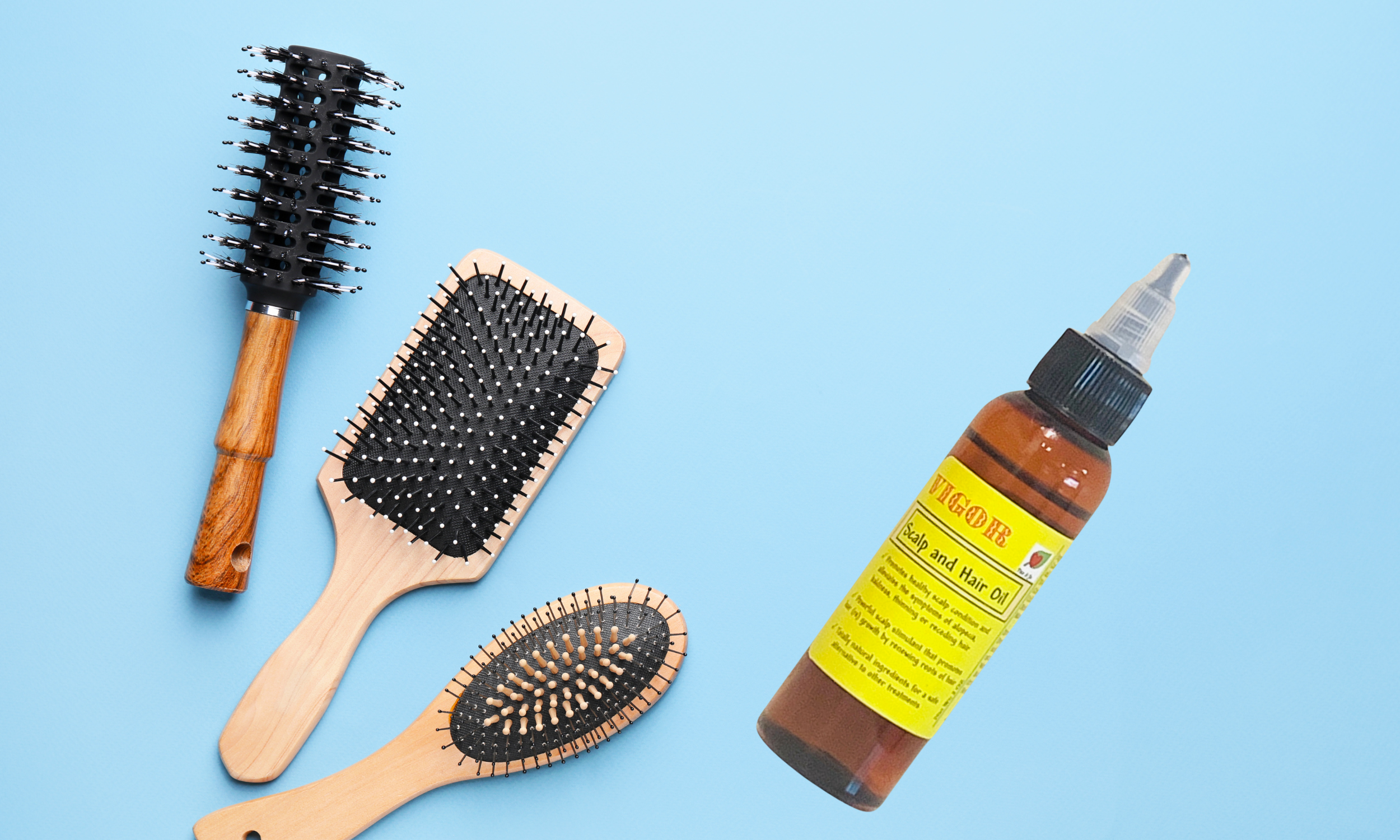 Hairbrushes and hair oil on a light blue background.