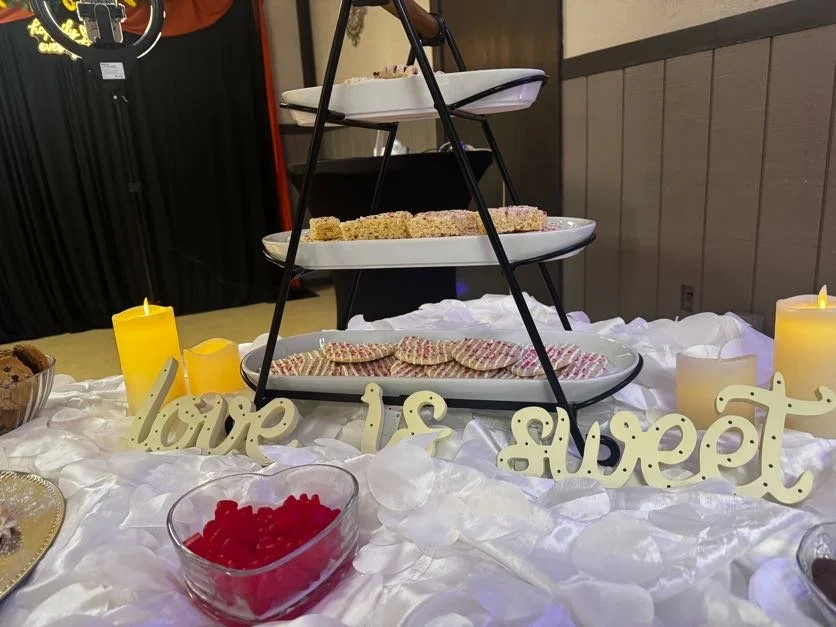 A section of a cookie table at Center Stage featuring a three-level cookie towers and a sign that reads "love is sweet",