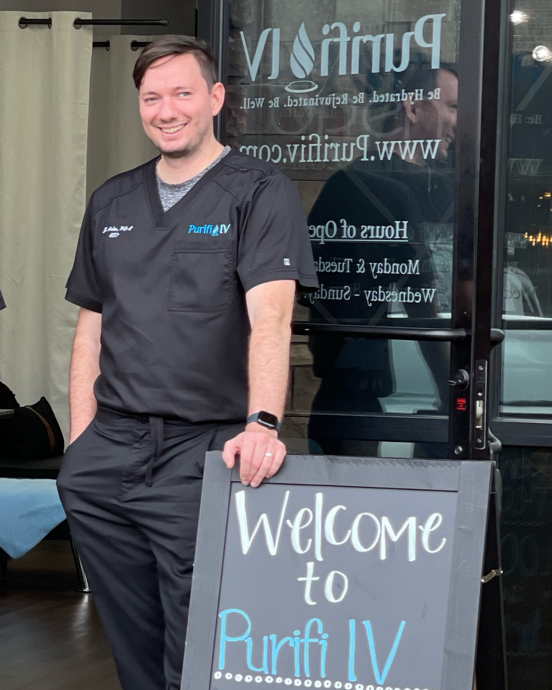 A man standing outside a business with a sign that reads Welcome to Purifi IV.