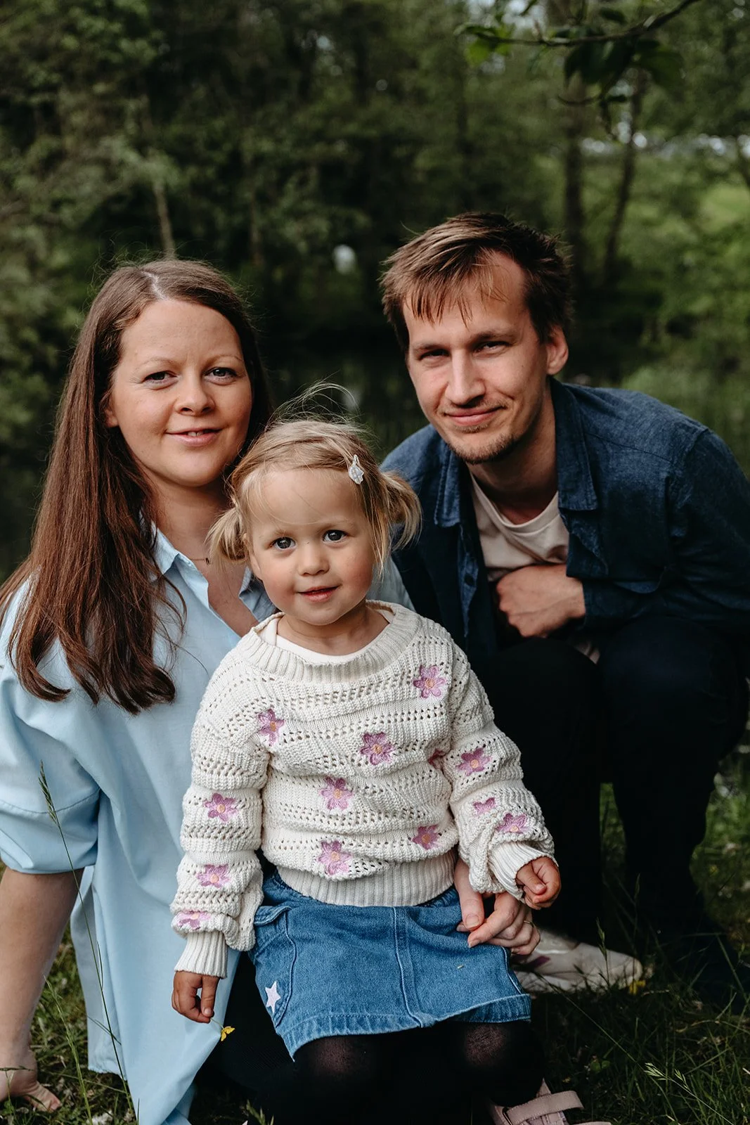 Familieportrett av mor, far og liten jente i skogen