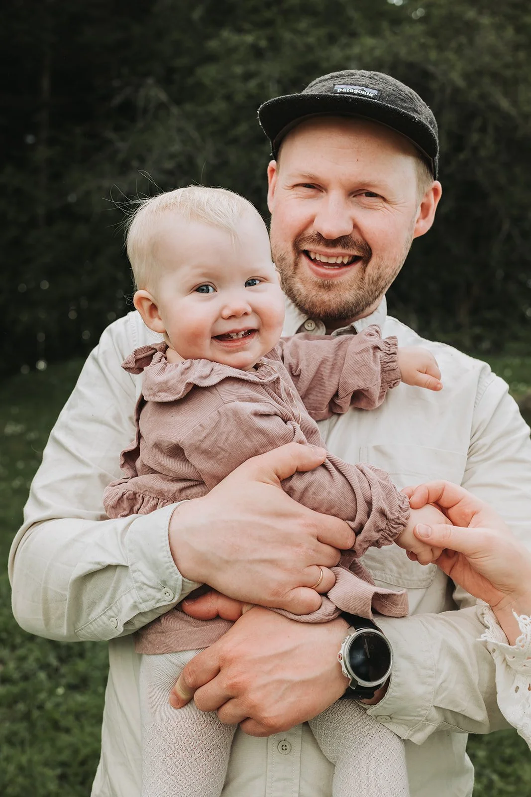 Smilende far holder en glad baby i armene utendørs i en skog