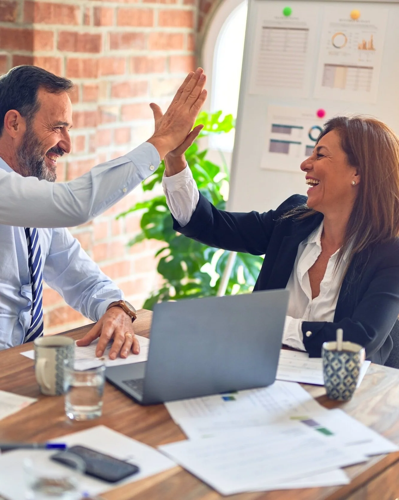 professionals-smiling-and-high-fiving-in-a-happy-office-setting