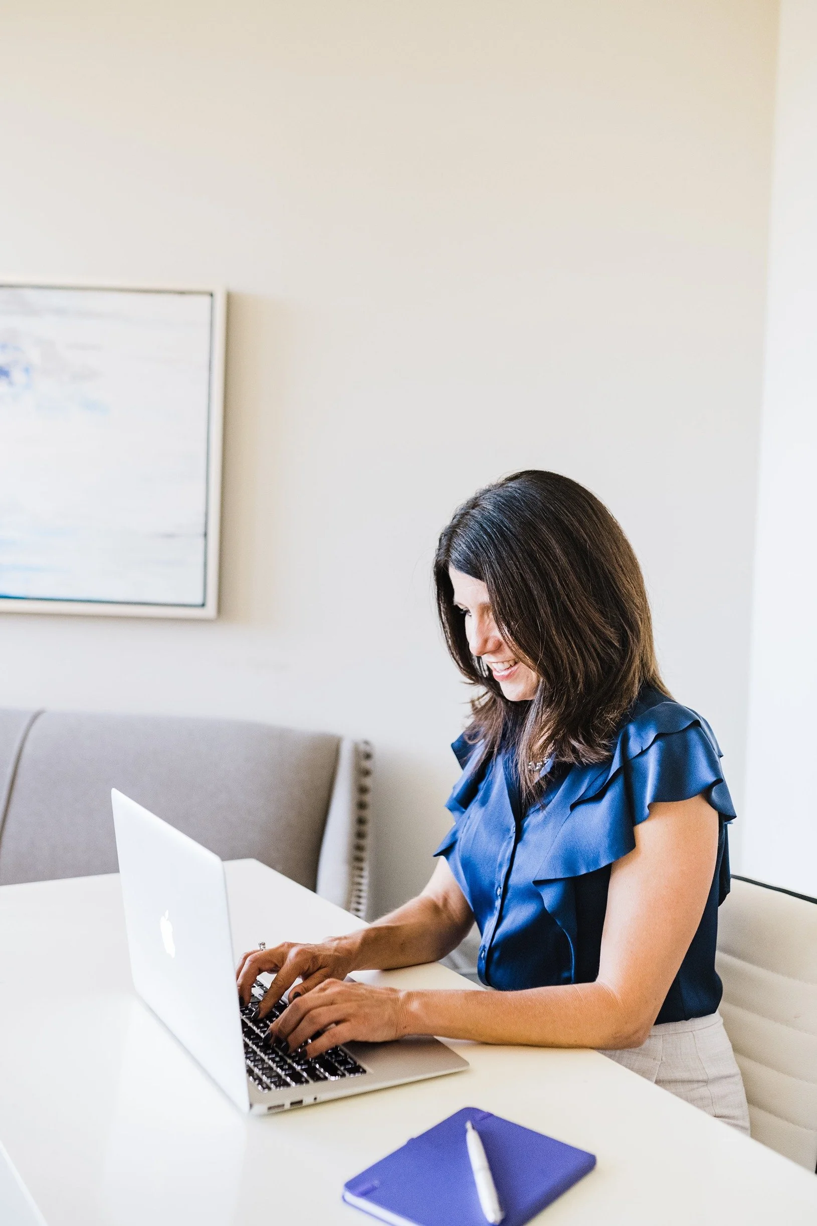 rachel fry sitting at desk with blue notepad and typing on laptop