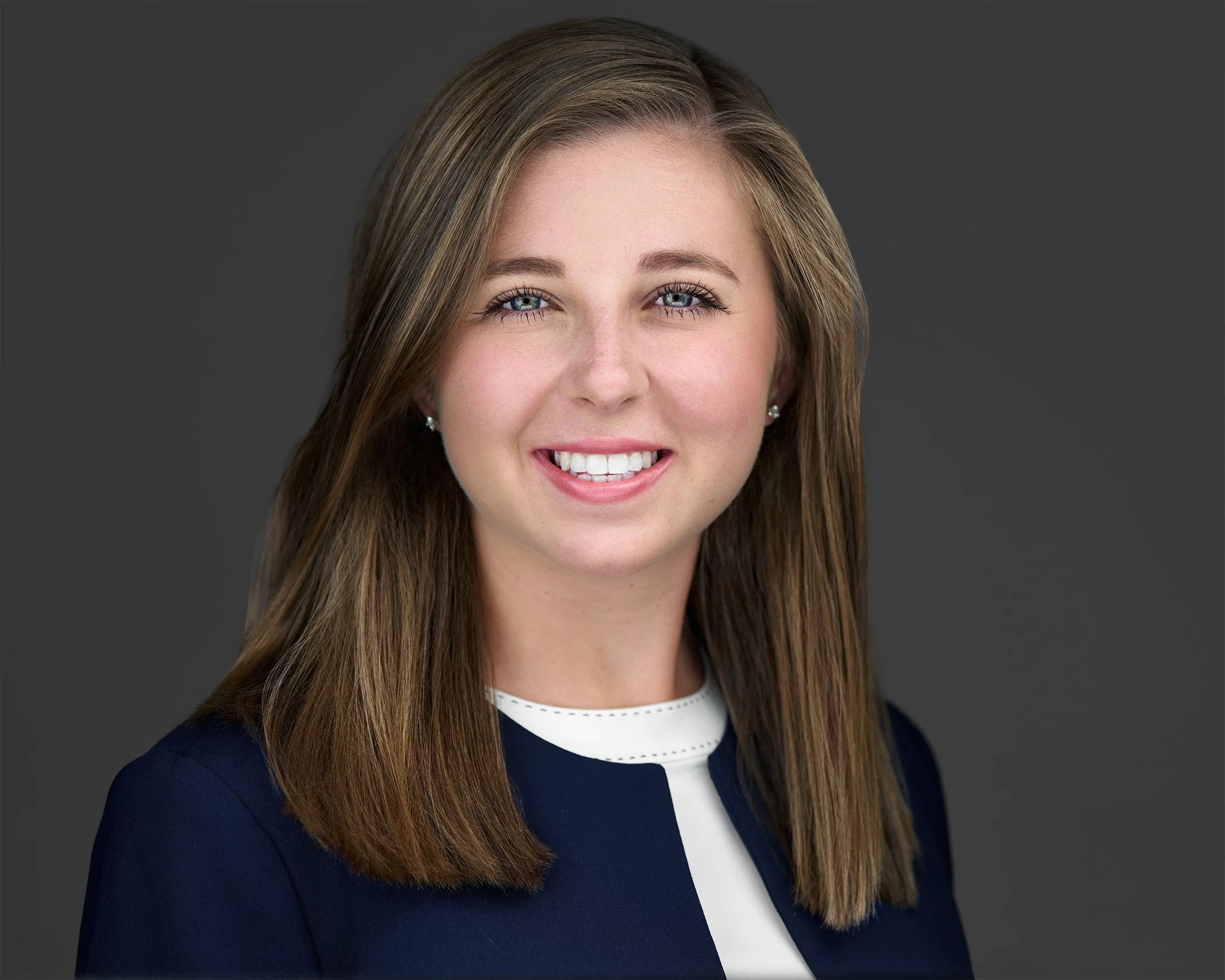 A professional headshot of Haley Nolen smiling, wearing a navy blue blazer and white top, against a gray background.