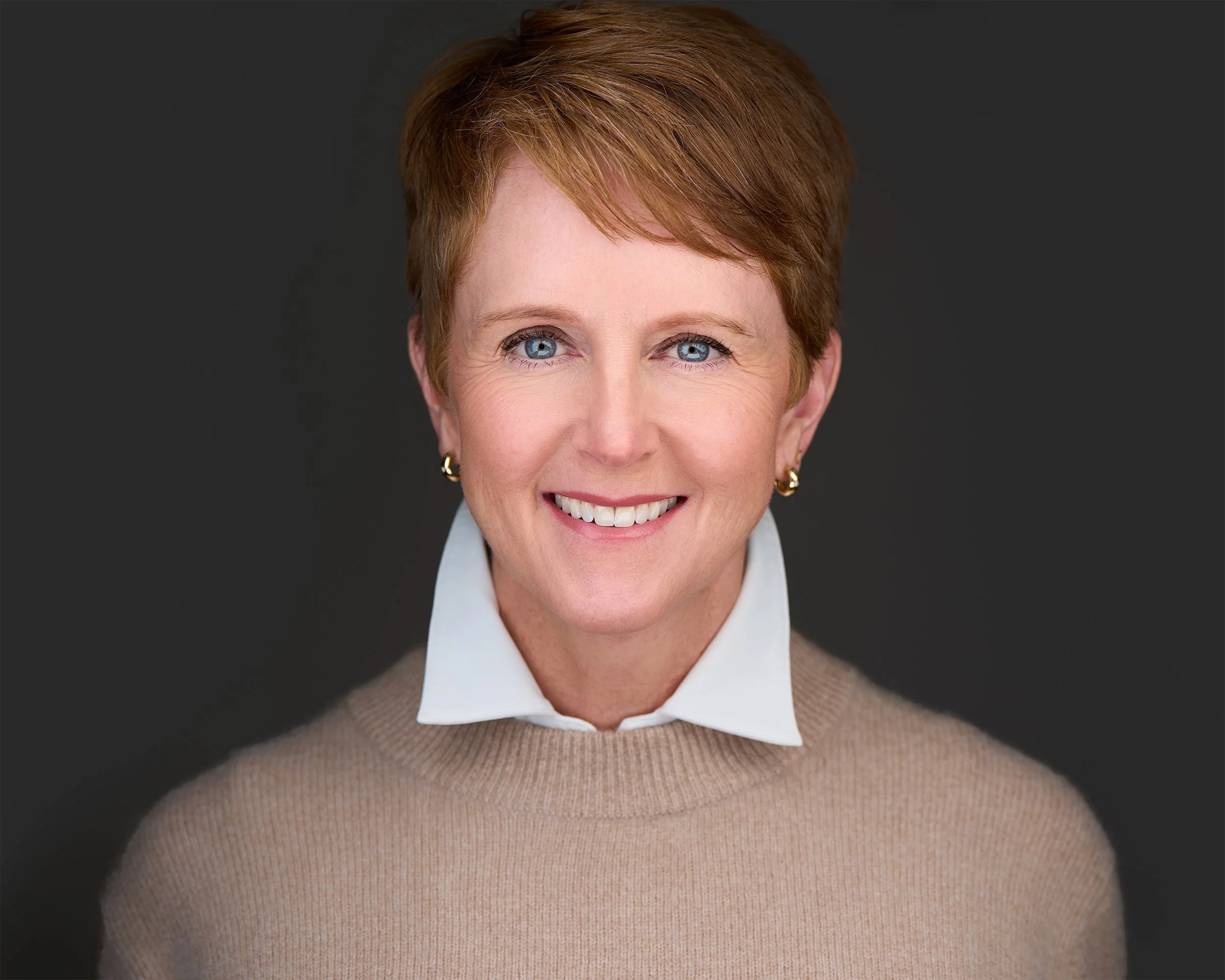 headshot of aimee puckett wearing a tan sweater with a white collar