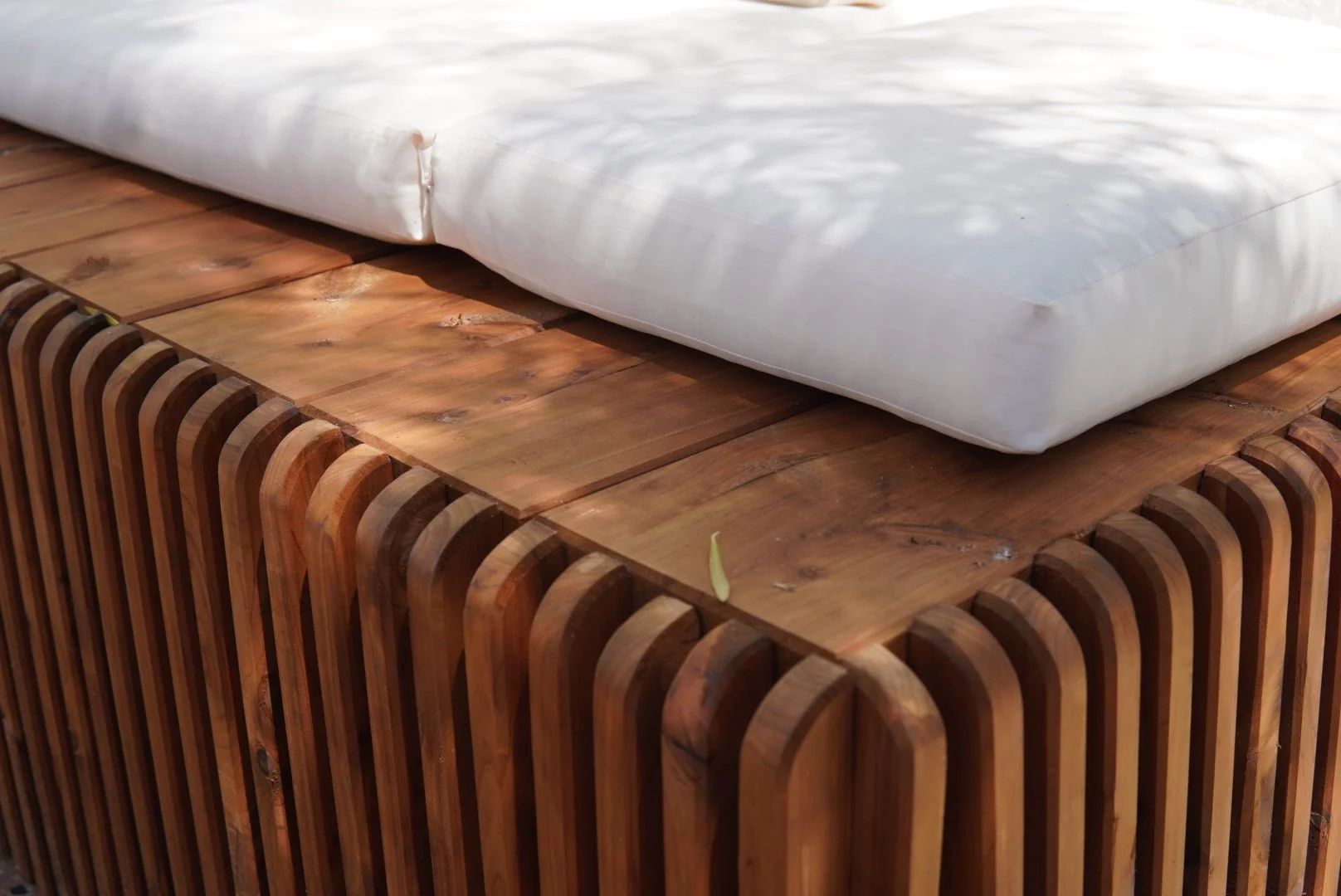 Close-up of a custom wooden bench with a white cushion.