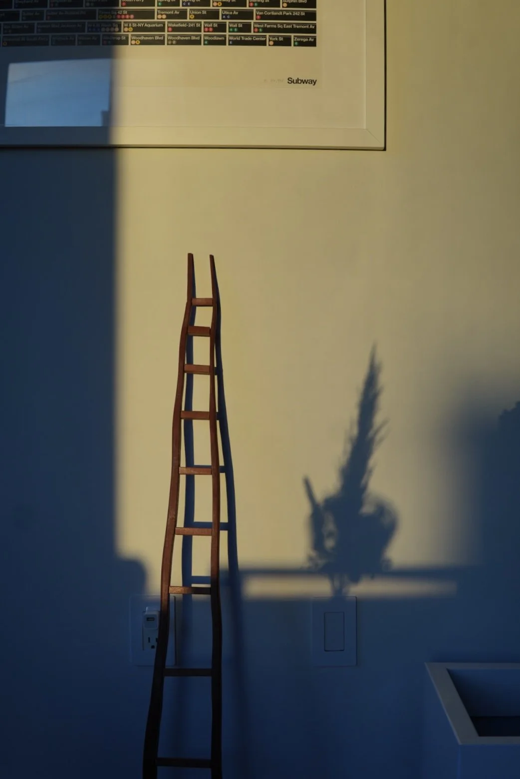 A miniature wooden sculpture casting a shadow on wall lit by morning light.