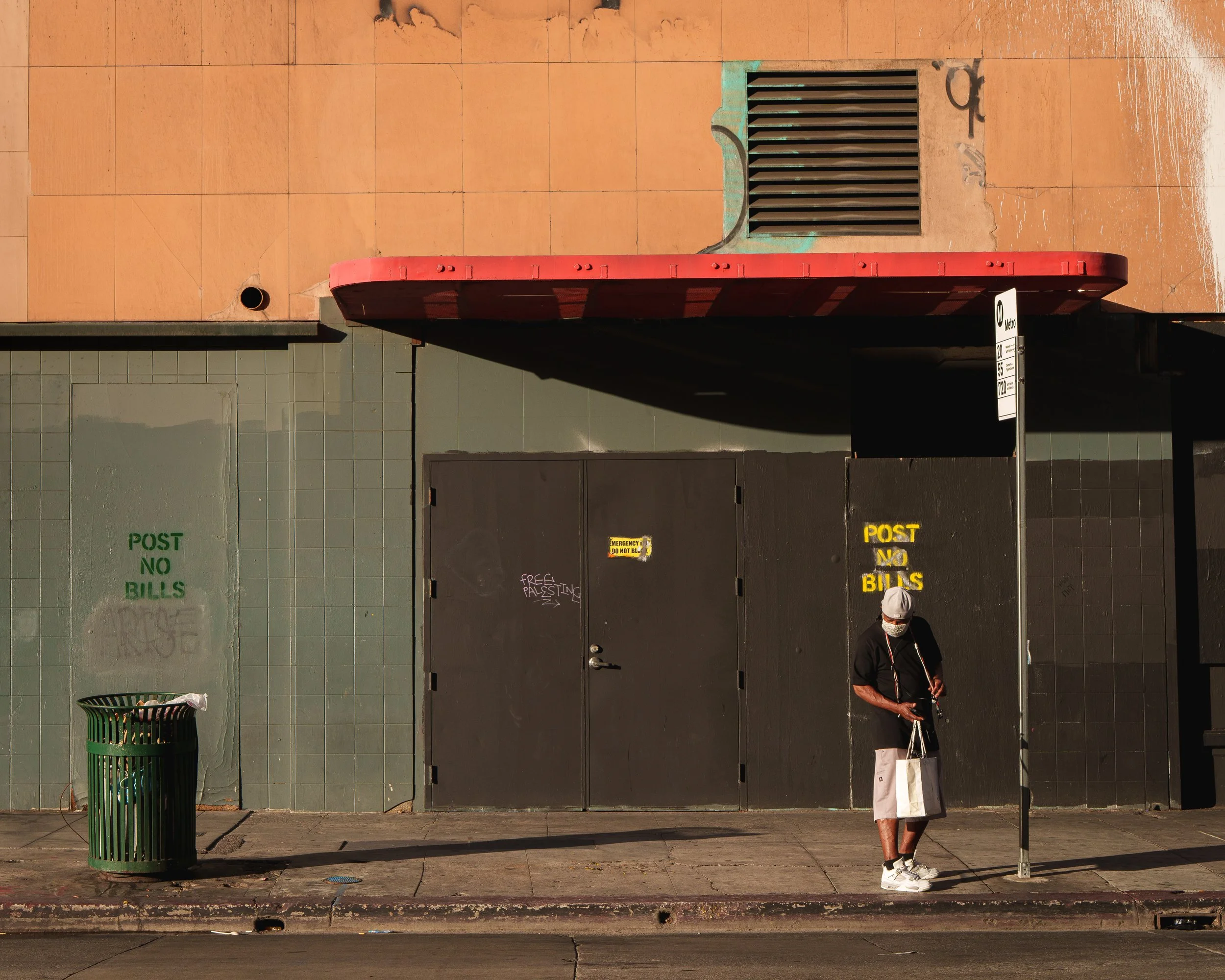 Man with protective mask standing in front of a closed and vacant building