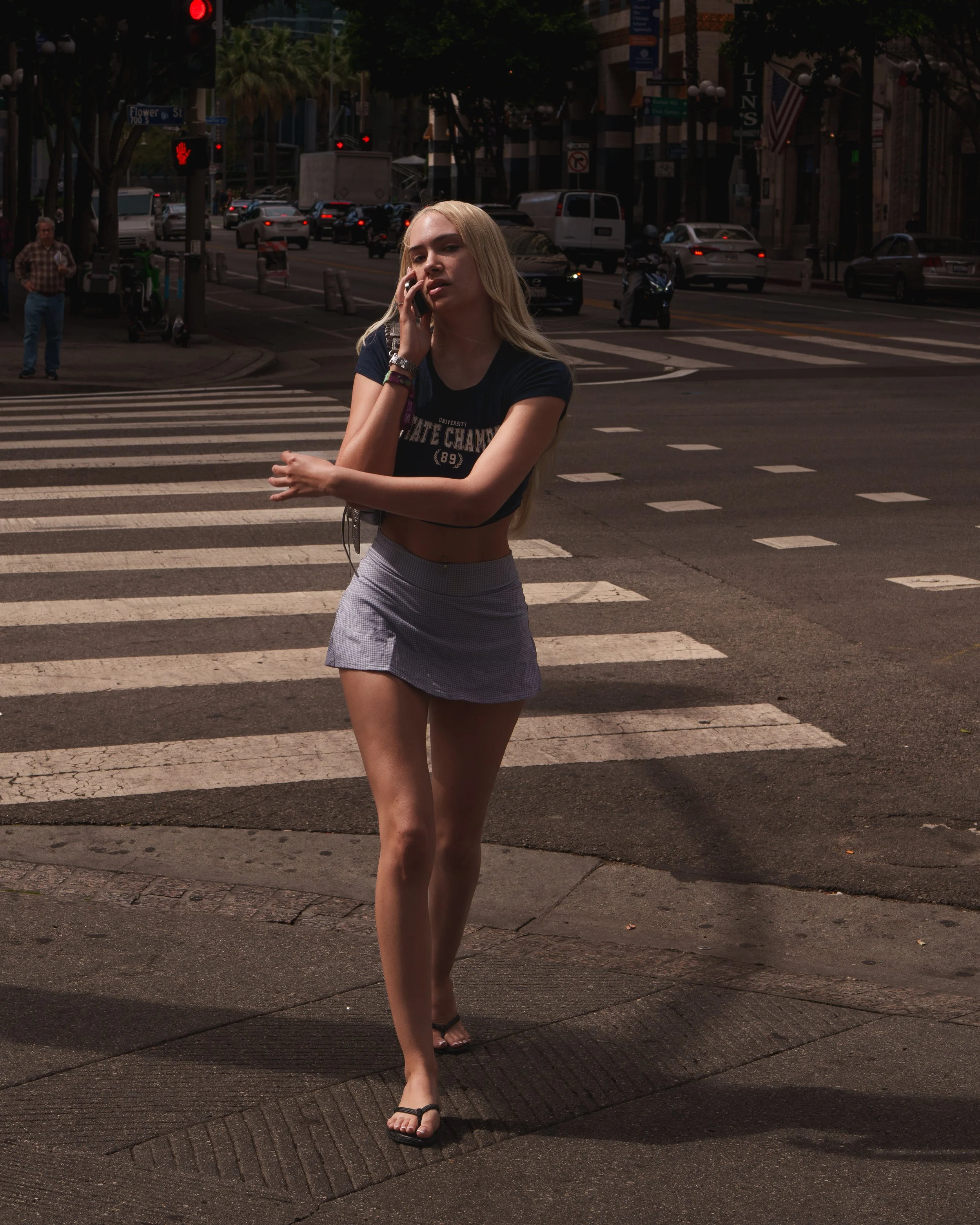 Tall girl with long legs walking across the street wearing a short skirt and t-shirt that reads State Champs