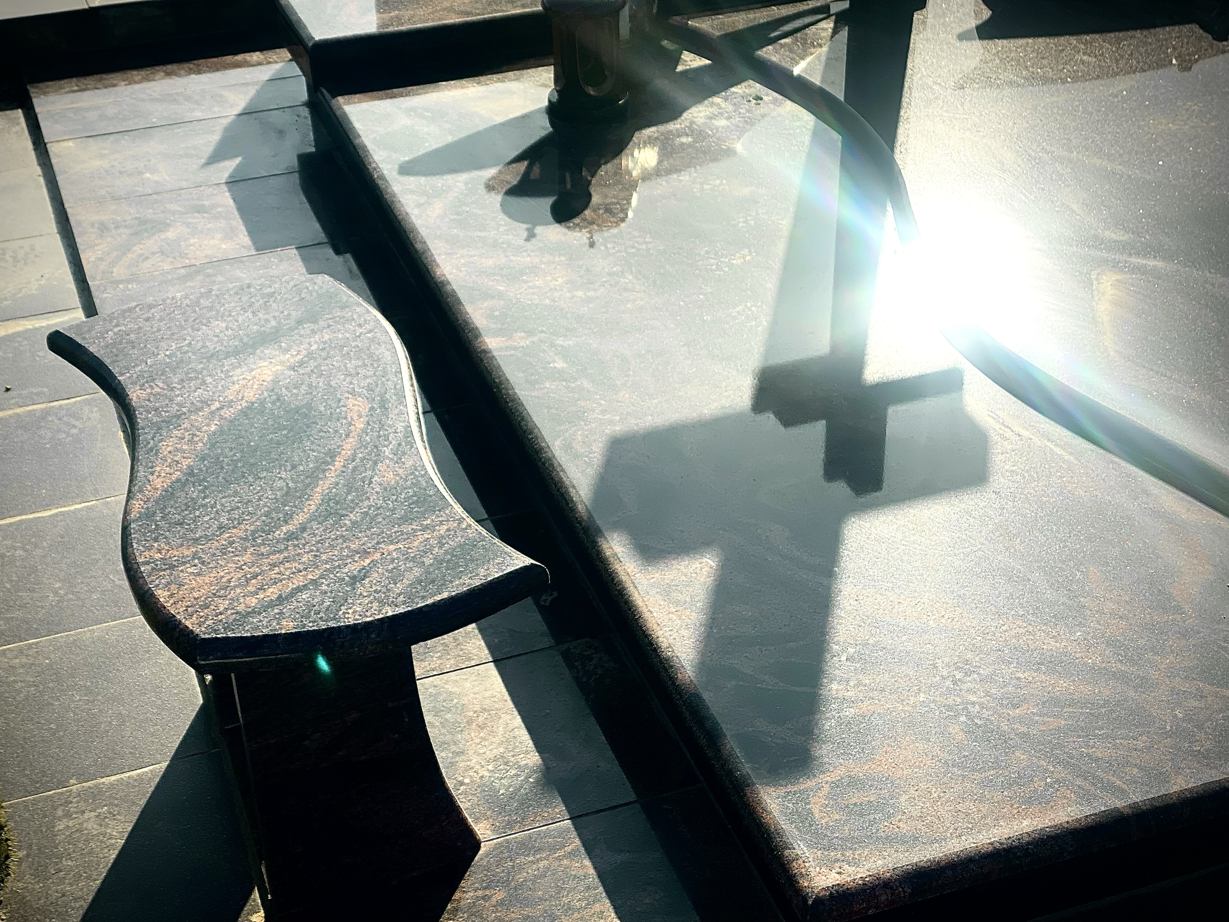Granite monument with cross shadow in sunlight