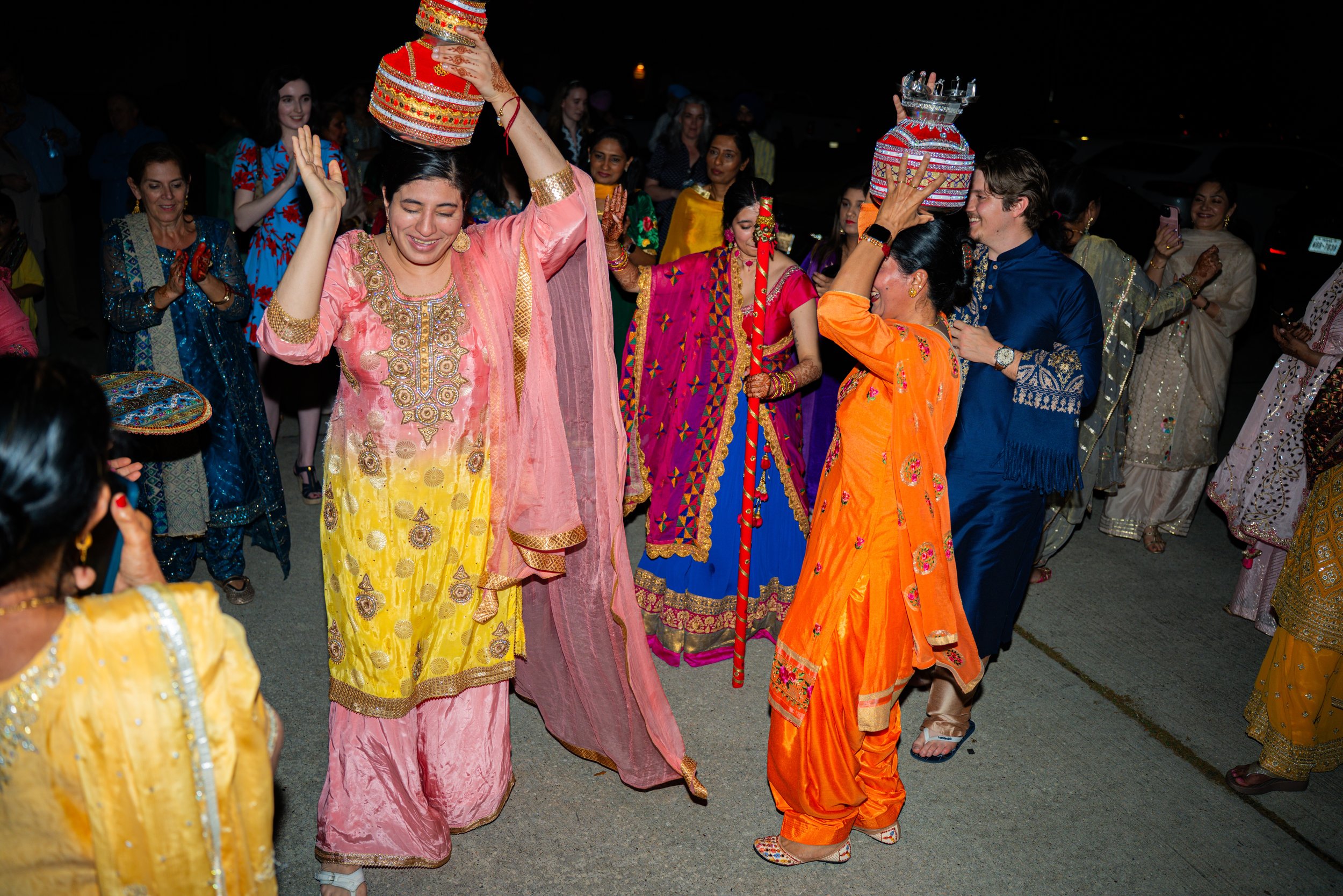 People dressed in colorful traditional Indian clothing dancing and celebrating at night.