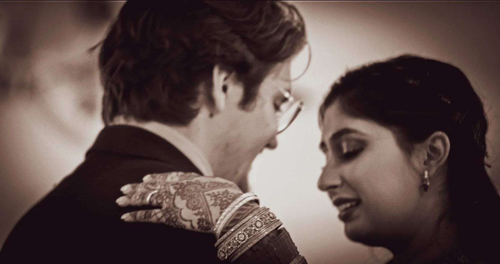 A black and white photo of a couple during an intimate moment, with their foreheads touching and eyes closed.