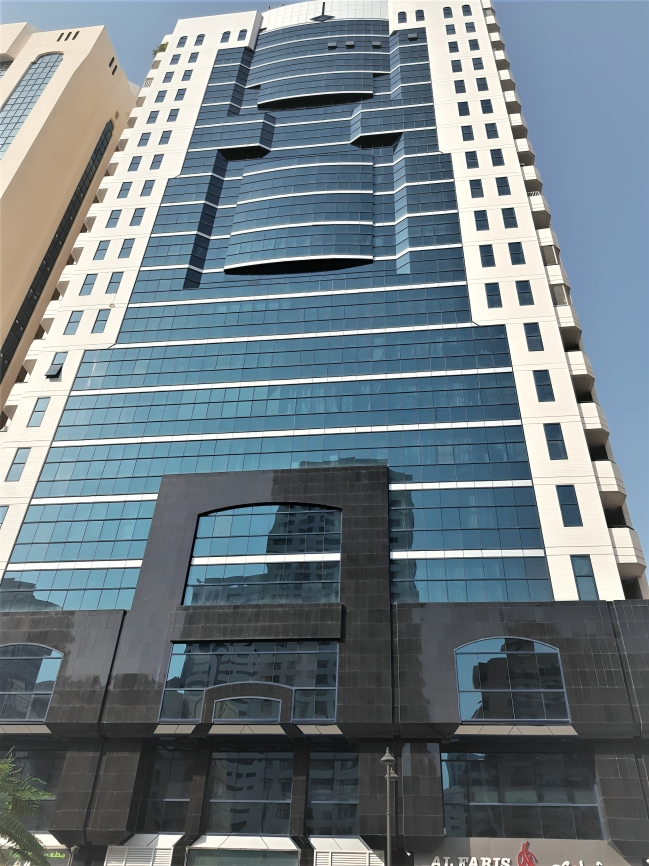Tall modern building with a mix of glass and concrete facade, featuring geometric patterns and large windows.