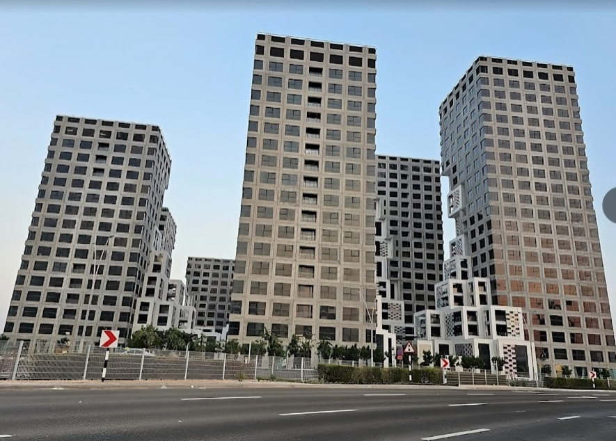 Tall modern office buildings with geometric window patterns lining a road.