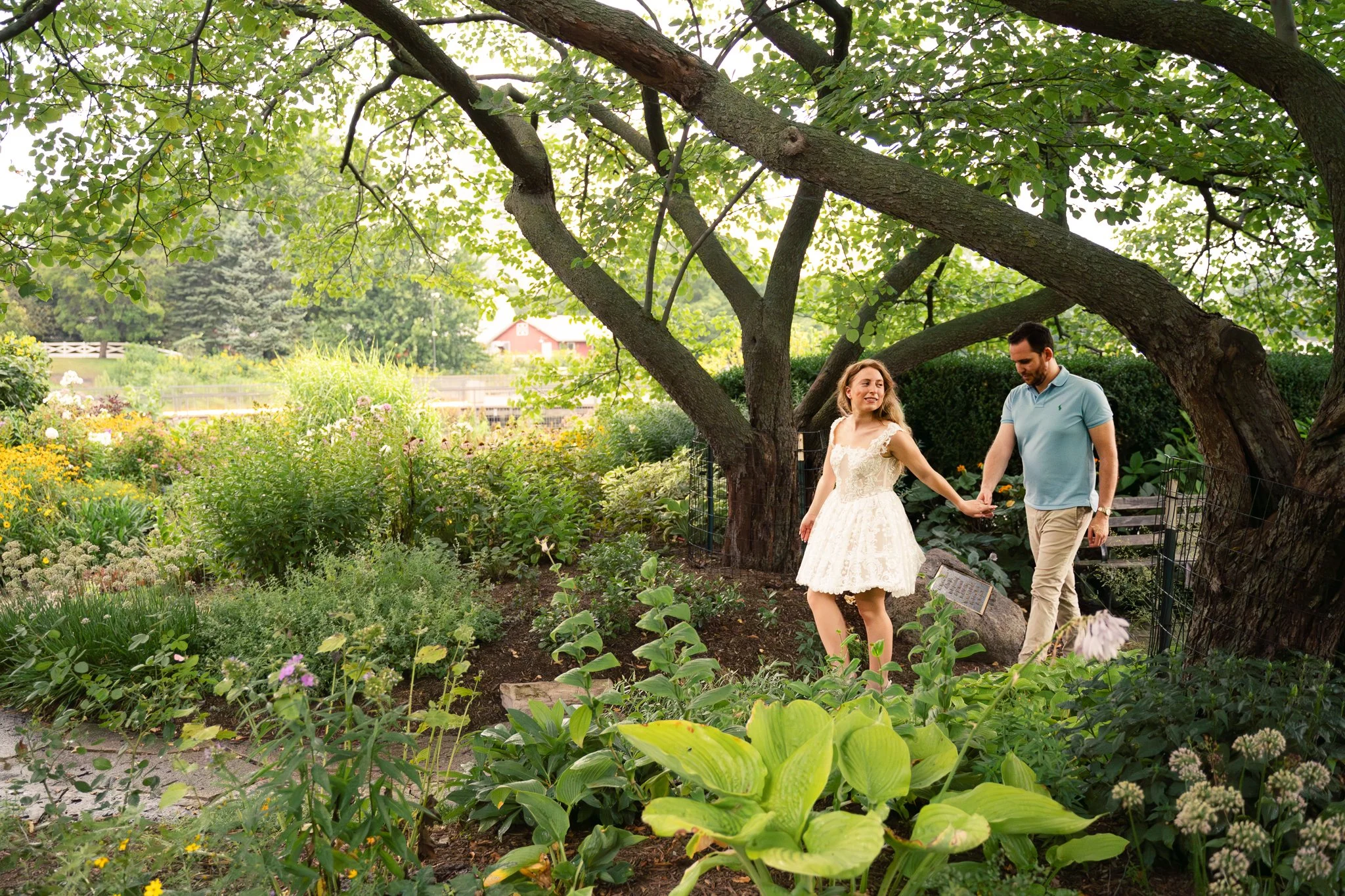 Lincoln Park Chicago Illinois Engagement Photographer | Bride in lace white dress holding hands with groom walking in secret garden | Midwest Wedding and Engagement Photography Sessions