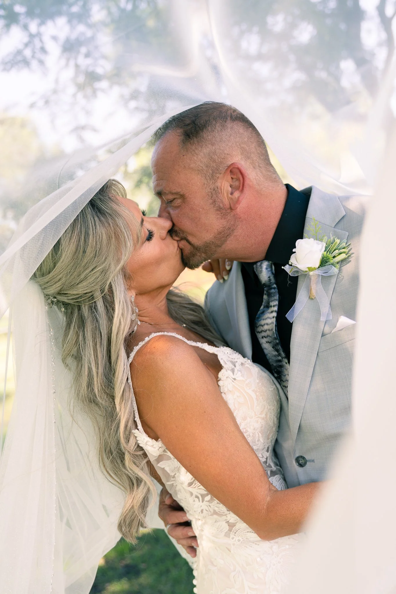 Hartland Wisconsin Wedding Photographer | Bride and groom kiss under veil in dappled sunlight