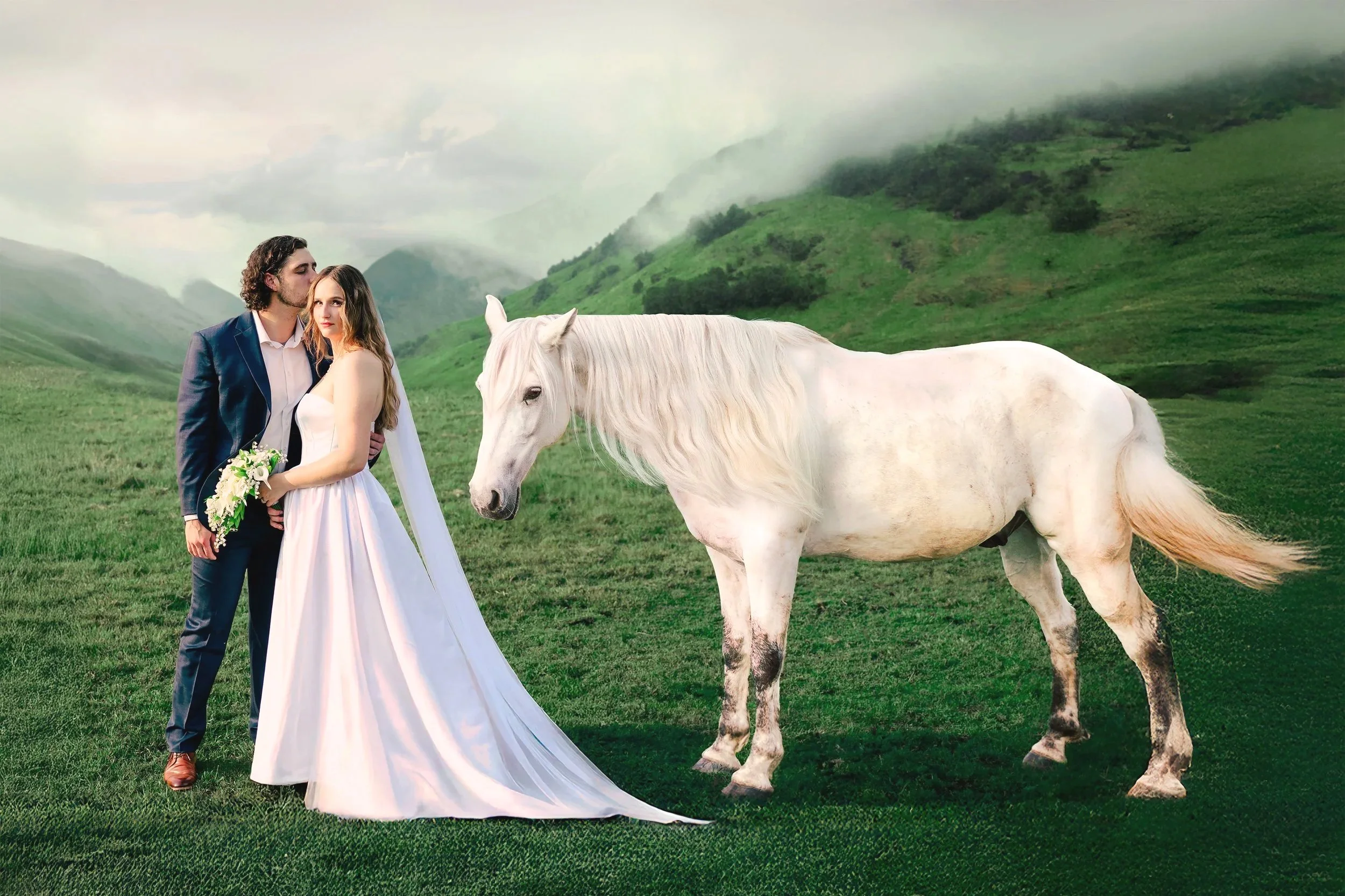 A bride and groom standing together outdoors on a grassy plain with green hills and misty mountains in the background. The groom has dark curly hair, wearing a dark blue suit and brown shoes. The bride has long light brown hair, wearing a white wedding gown and holding a bouquet of white flowers. A white horse stands nearby, facing the couple.