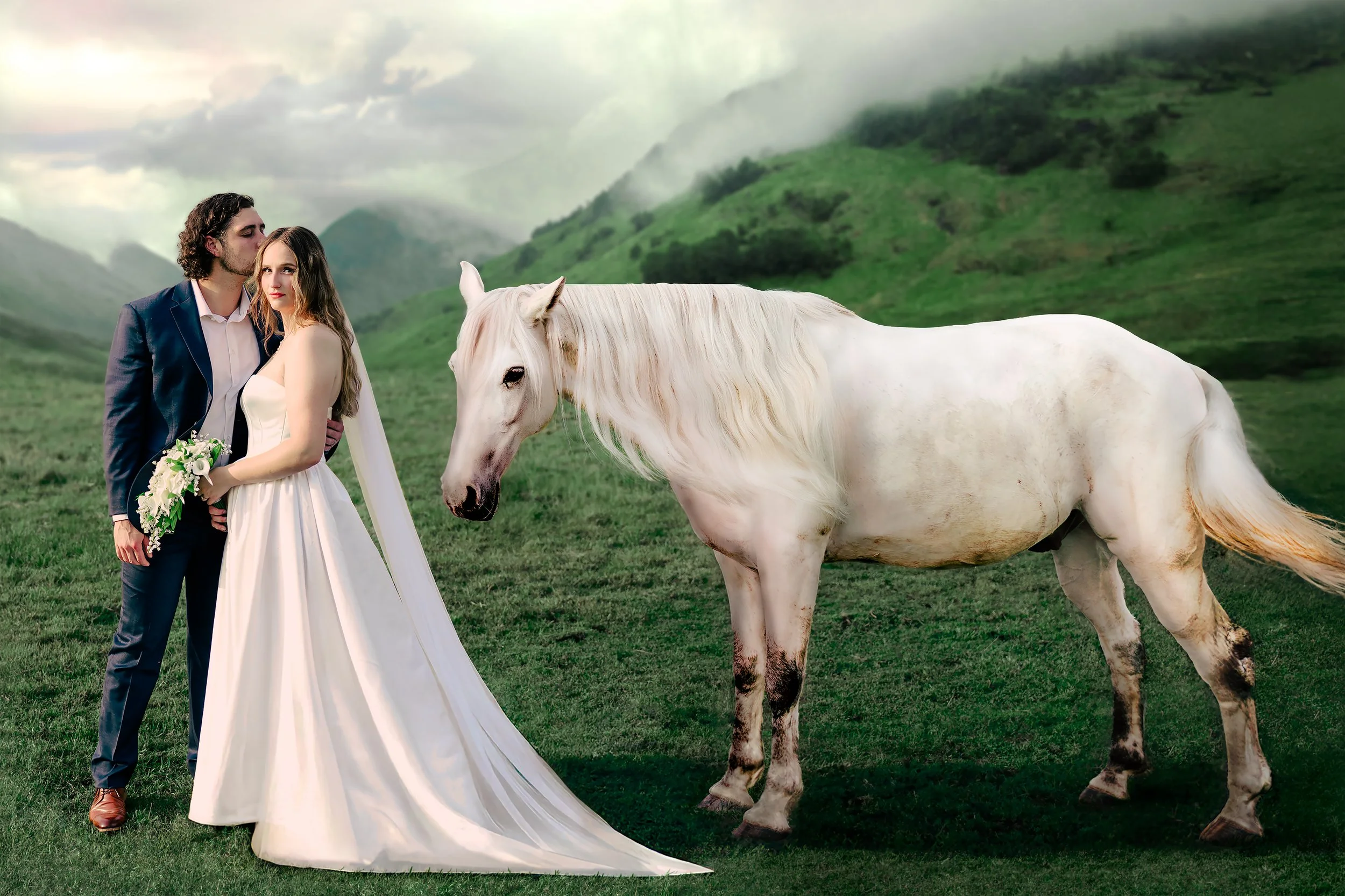 A couple dressed in wedding attire standing outdoors with a white horse in a green mountainous landscape.