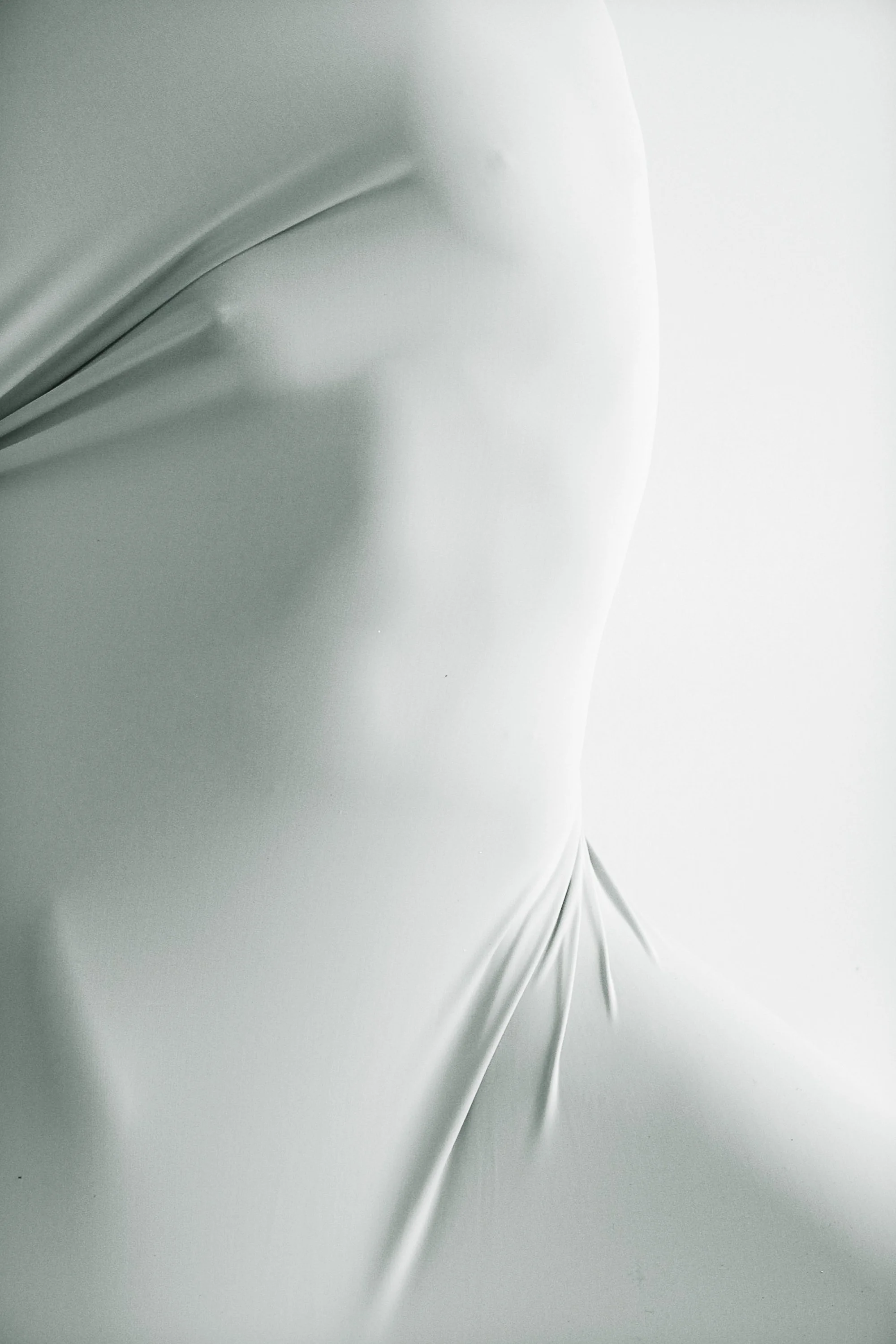 Close-up of a smooth, shiny, white surface with creases, possibly fabric or plastic.