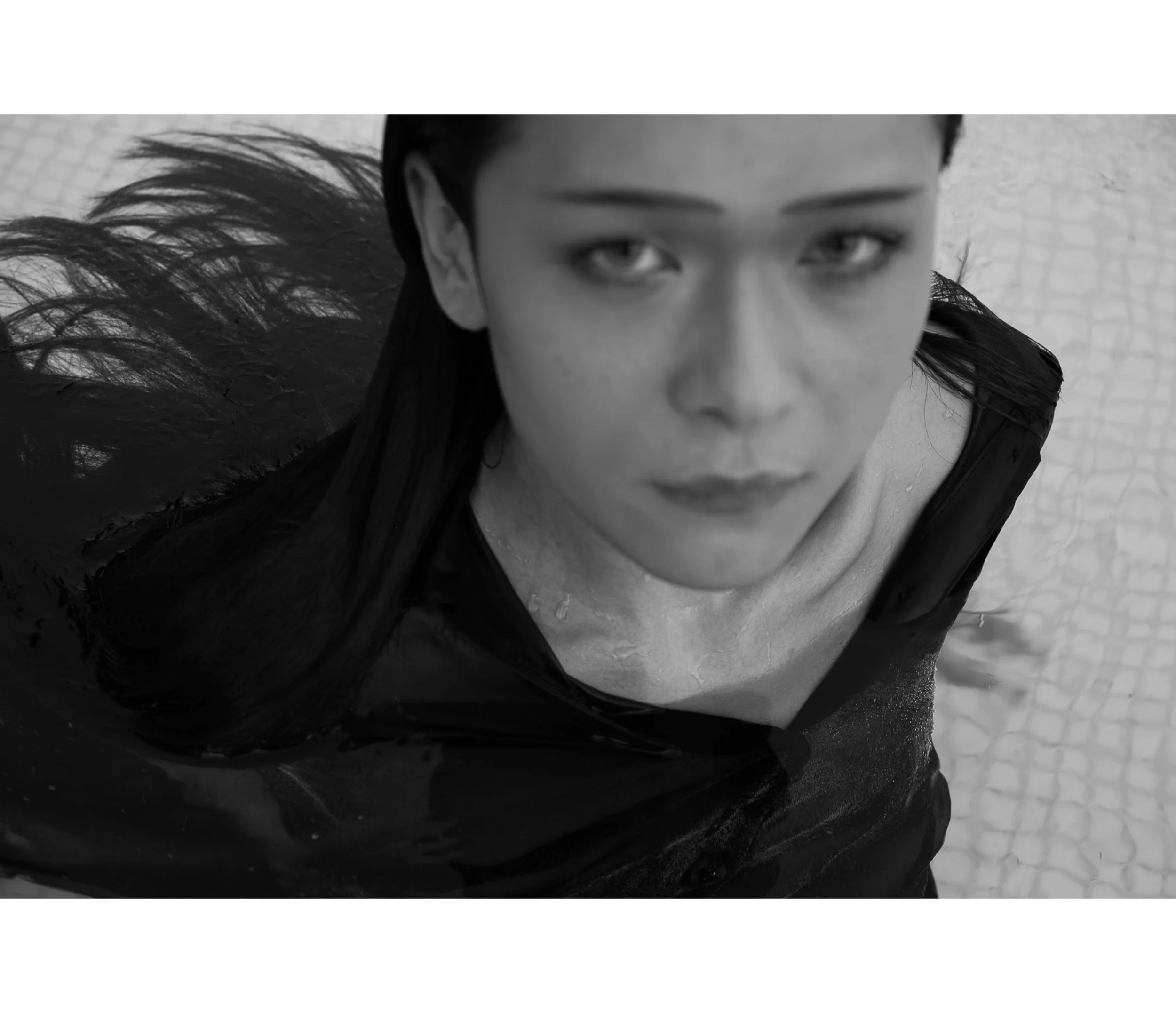 A woman with wet hair and a serious expression looking up at the camera, submerged in water.