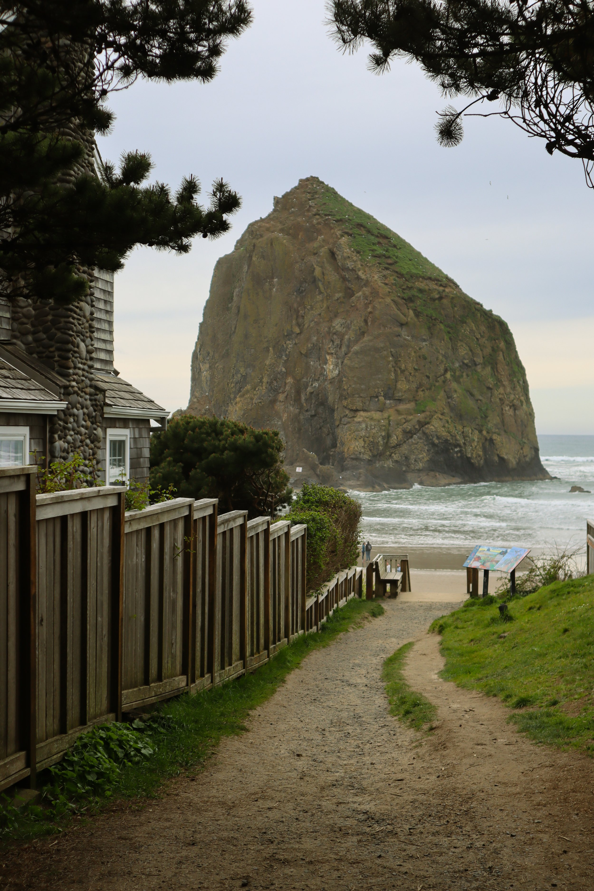 A breathtaking view of Cannon Beach in Oregon, featuring the iconic Haystack Rock rising from the sandy shore with gentle waves lapping at the beach. An essential stop for a perfect 4-day Oregon trip.