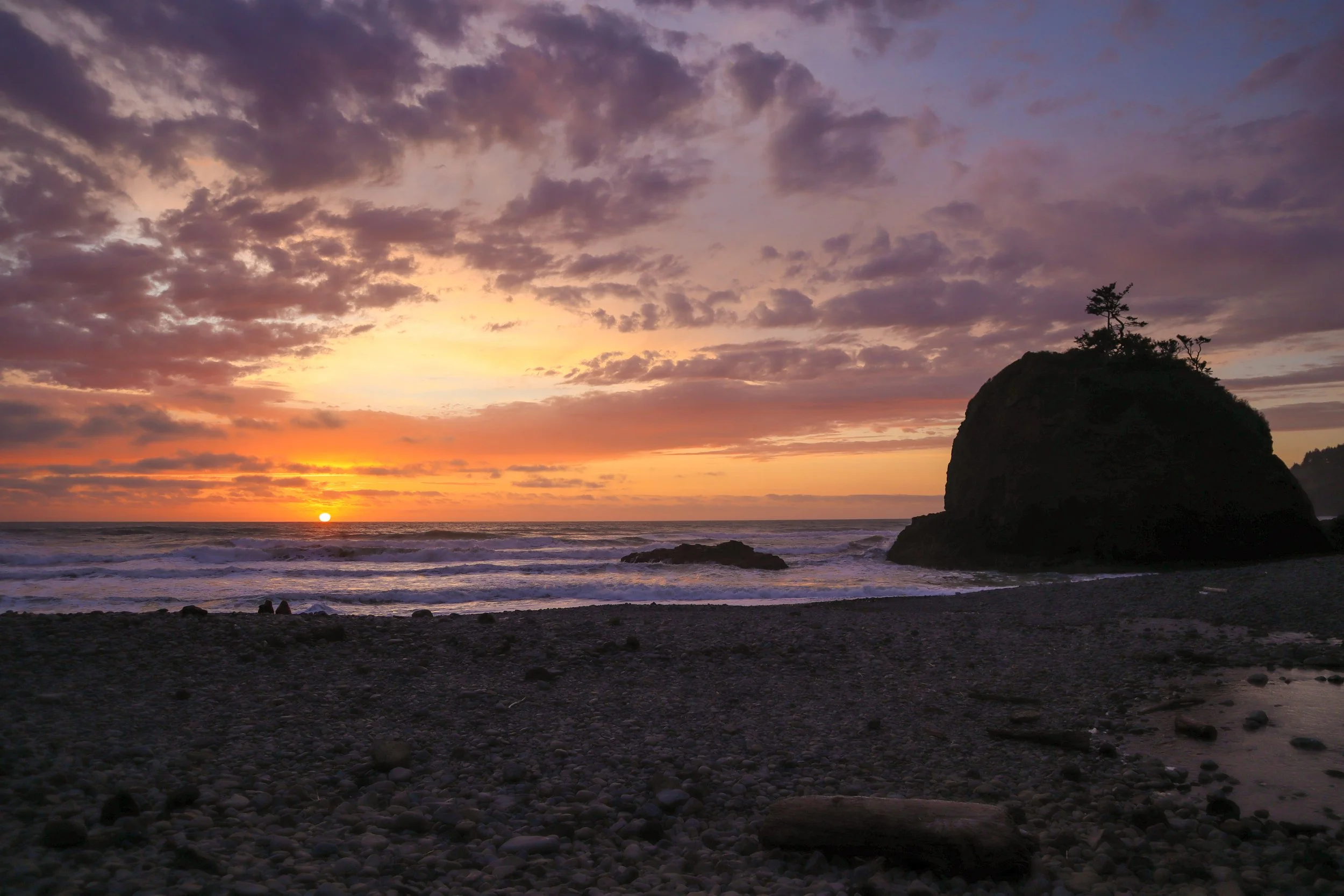 A serene view of Short Beach in Oregon, with rugged cliffs, smooth pebbles, and gentle waves rolling onto the shore. A peaceful stop on a perfect 4-day Oregon trip.