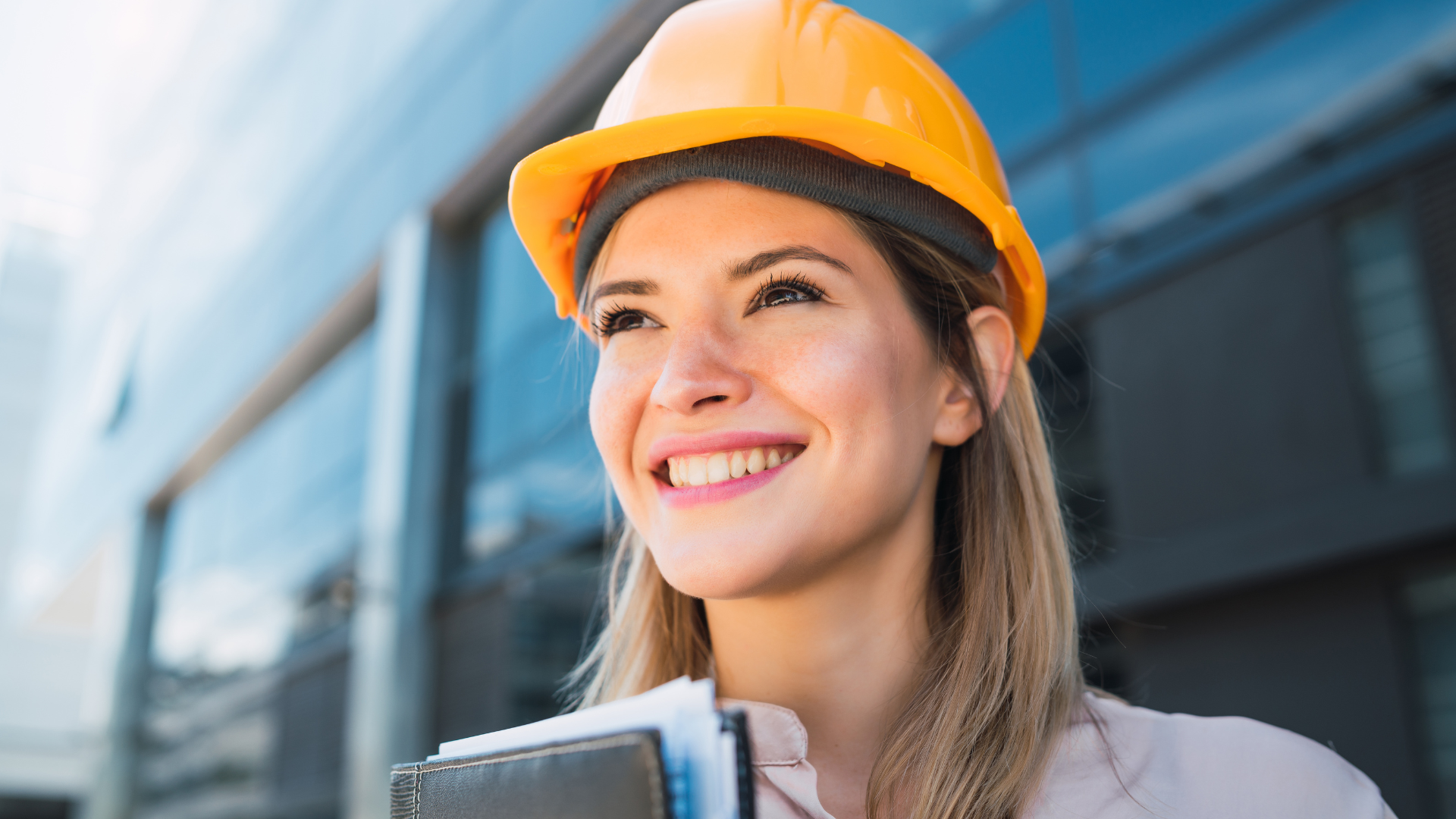 woman with blonde hair smiling wearing an orange hard hat