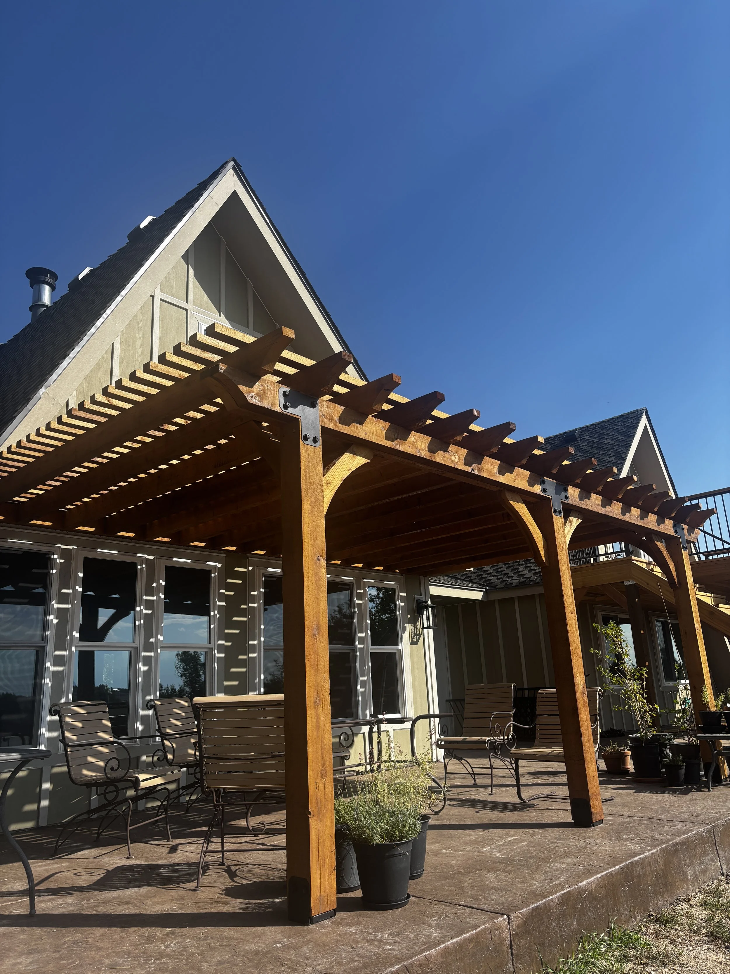 Cedar wood pergola off the back of a house.