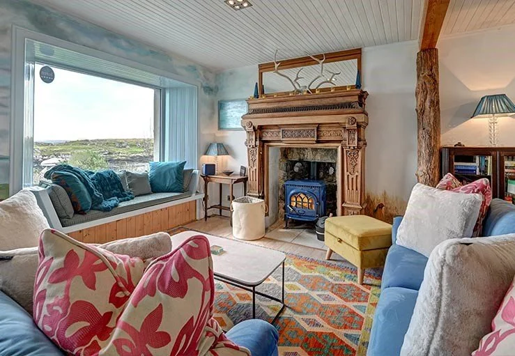 Cozy living room with a stunning sea views, wood burning stove, large window seat with velvet sofas