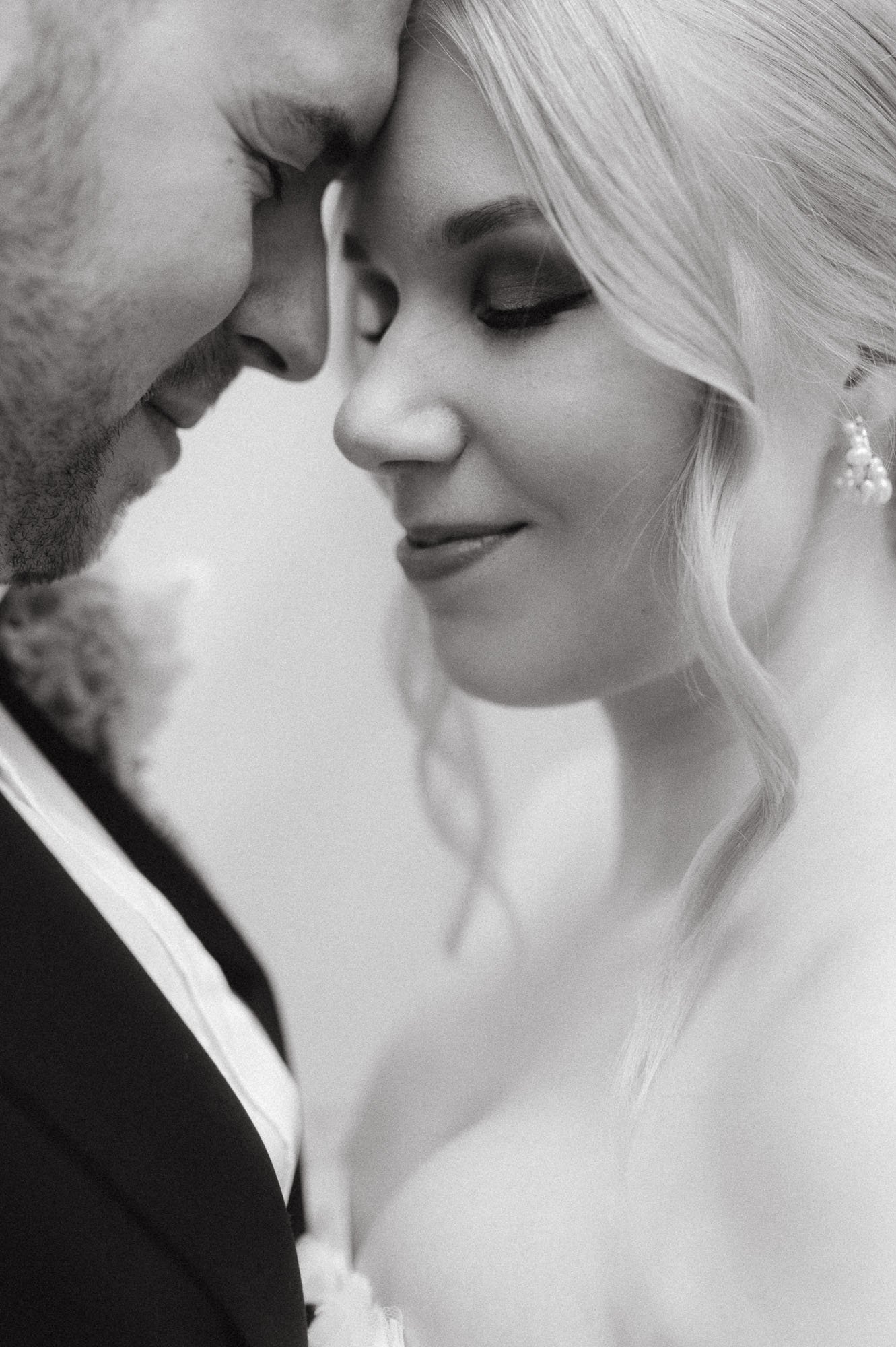 Hääpari, jossa mies ja nainen, koskettavat otsiaan ja hymyilevät.