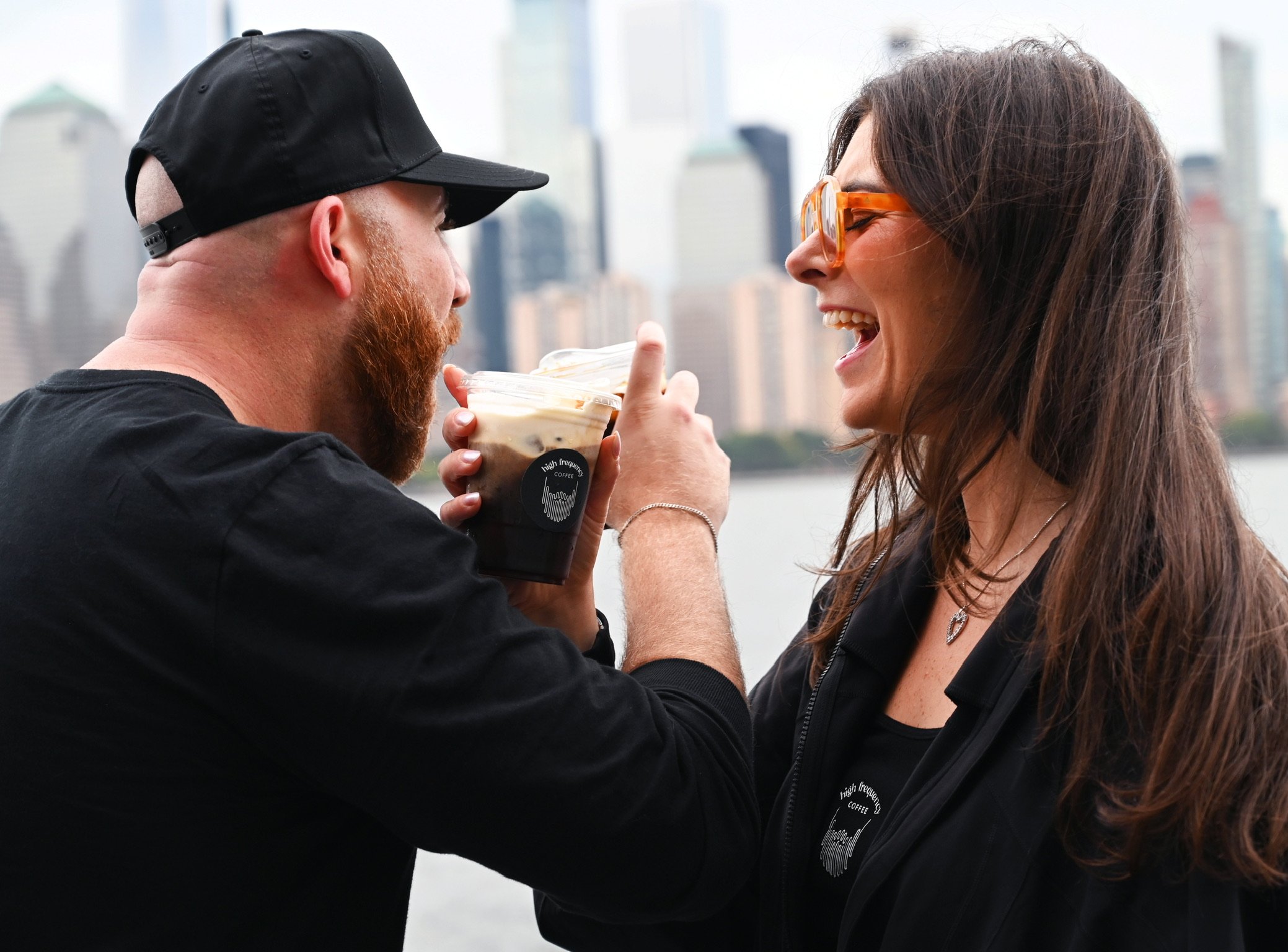 A man offering a woman a drink with a city skyline in the background.