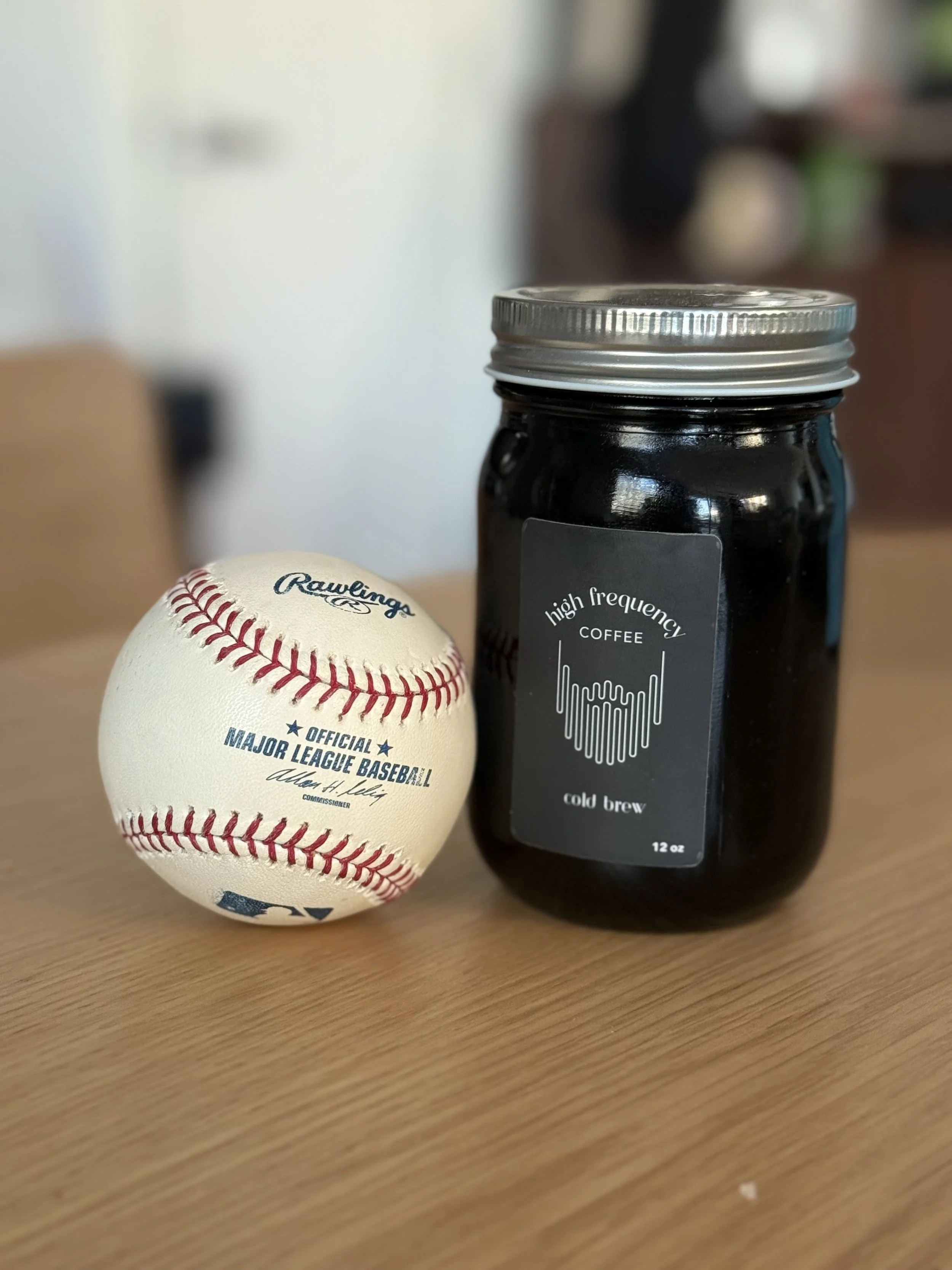 Baseball and a jar of cold brew coffee on a wooden table.