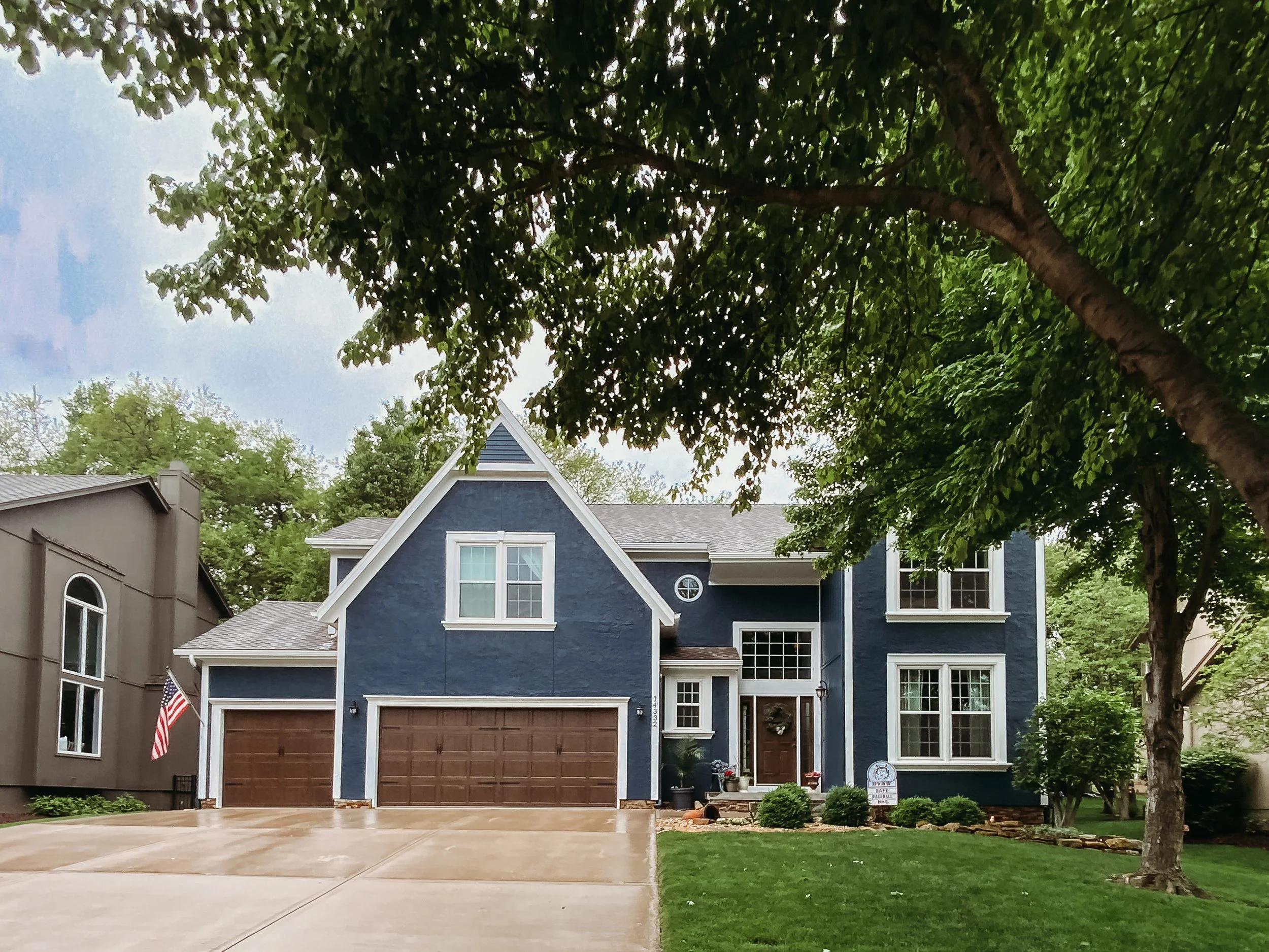 Completed Johnson County exterior painting with dark blue siding, white trim and brown garage doors.