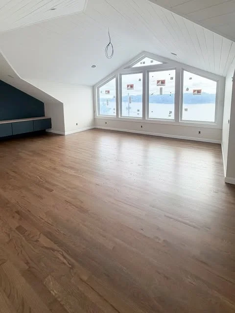 Bright finished interior with white walls, vaulted ceiling and wood flooring by Gripka & Co.